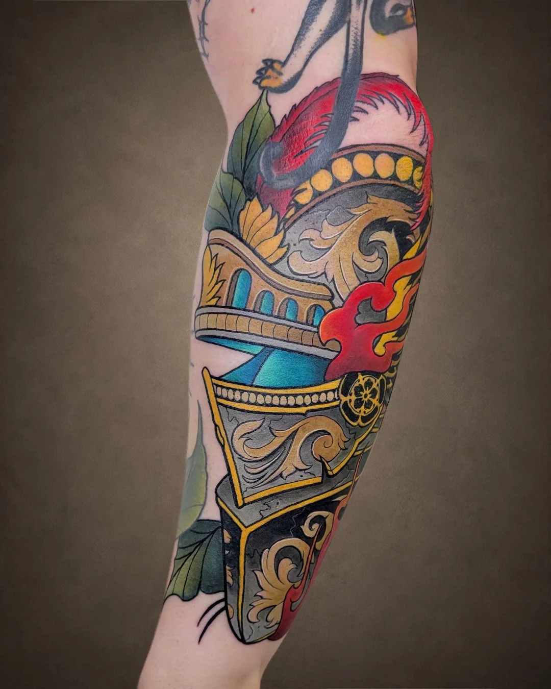 Colorful tattoo of a classical architectural piece with a red flame design on a person's arm.