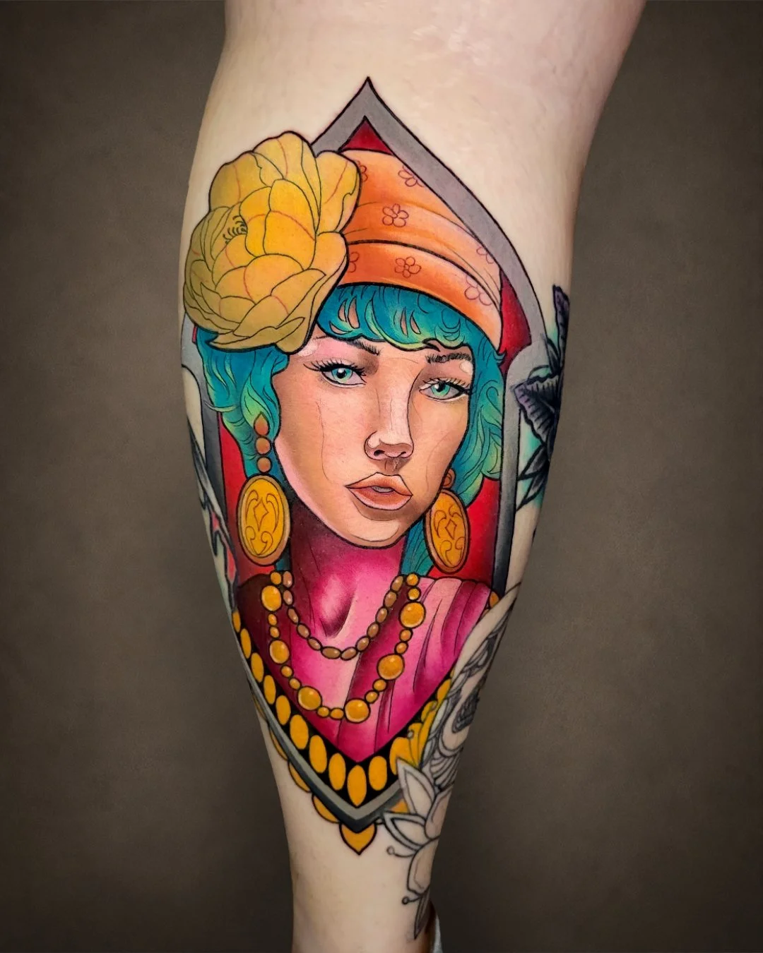Color Neo-Traditional woman portrait tattoo with turquoise hair, floral elements and ornamental jewelry.