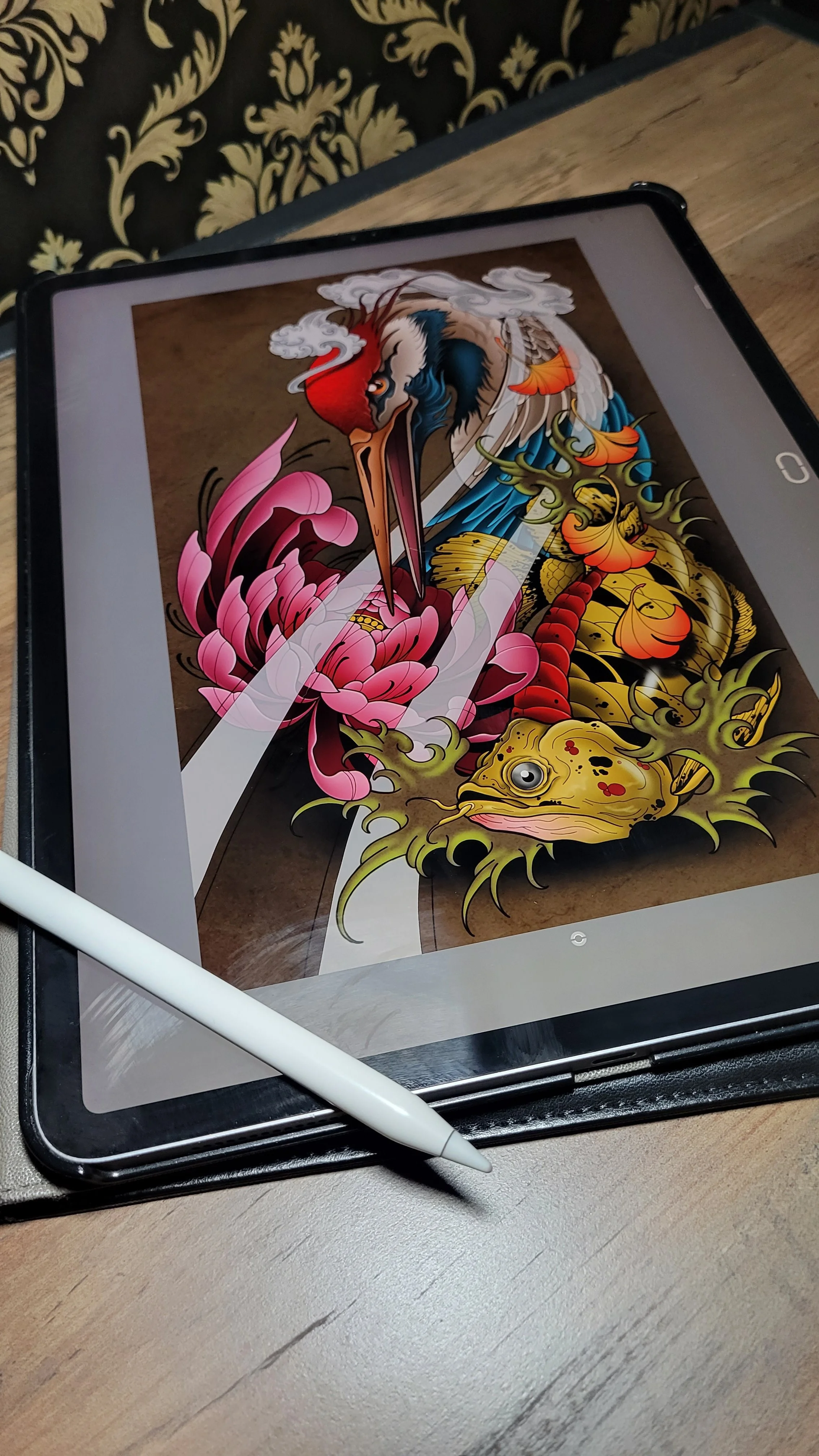 A tablet displaying a vibrant, traditional Japanese tattoo-style illustration of a heron, a koi fish, and floral elements on a wooden table, with a white stylus pen resting on the table.