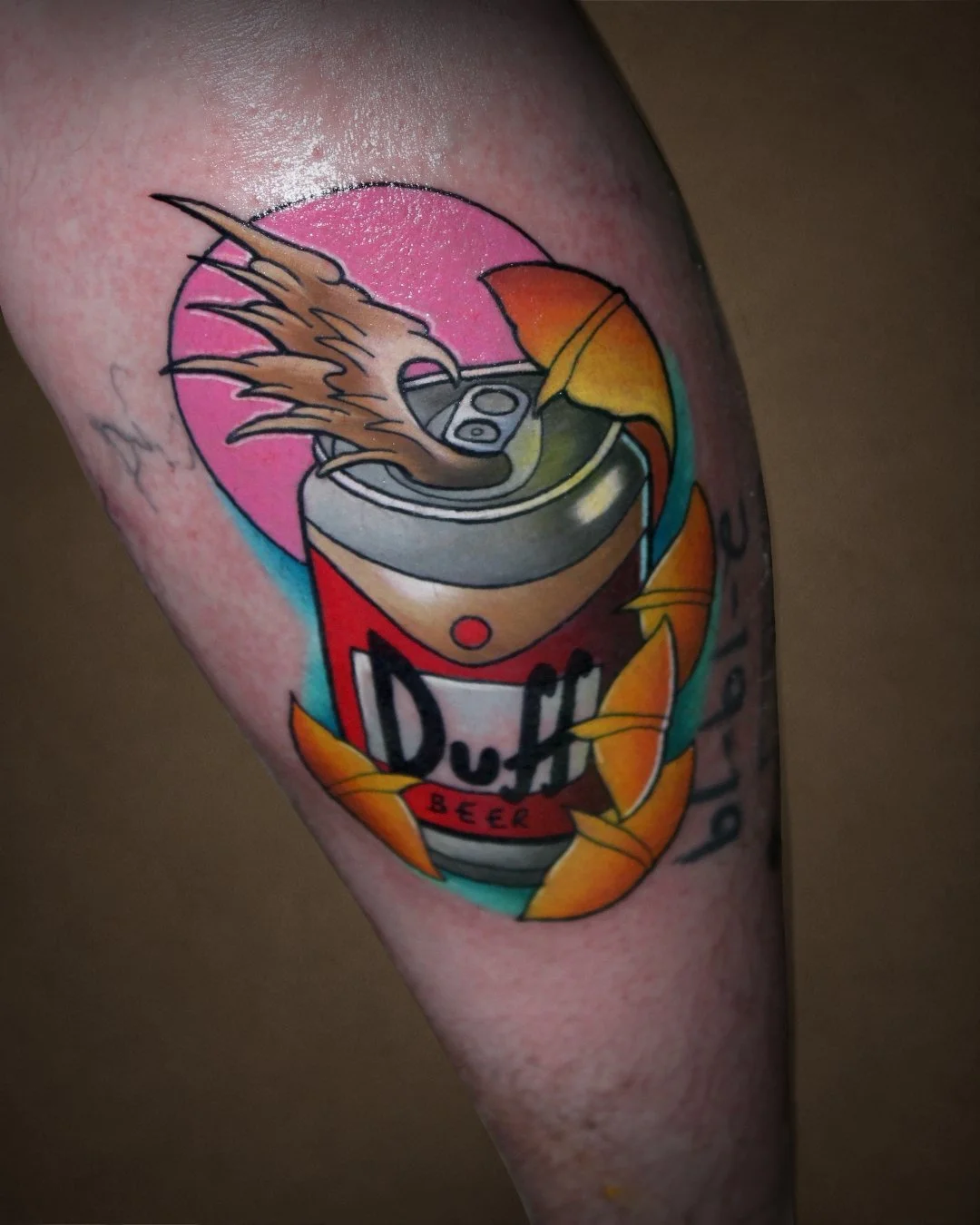 Tattoo of a soda can with a straw, surrounded by orange and yellow leaves, with a pink and blue background.