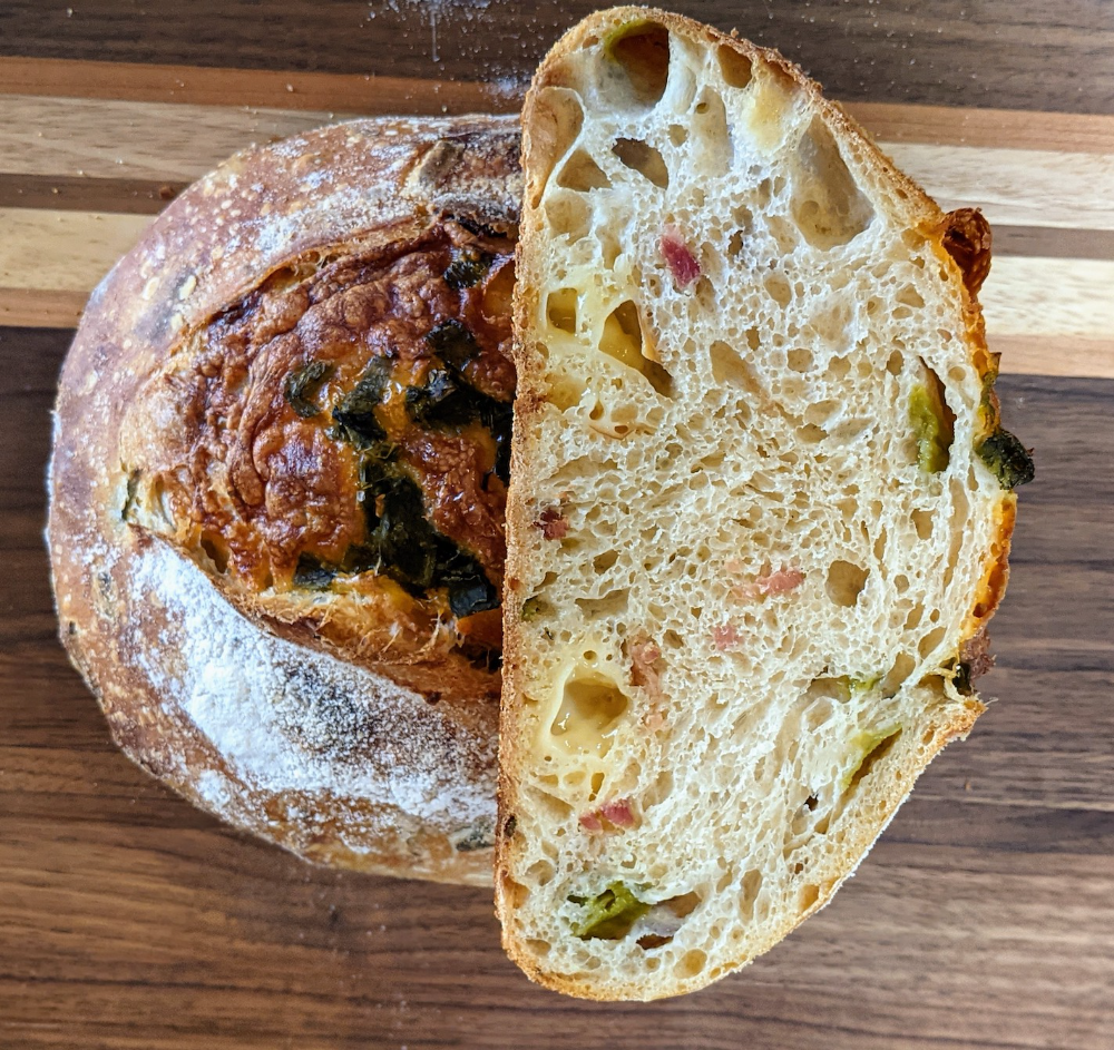 Artisan bacon and smoked Gouda sourdough loaf with a golden blistered crust, savory bacon pieces, and melted Gouda throughout, handcrafted at The Salty Mermaid Sourdough & Spreads.