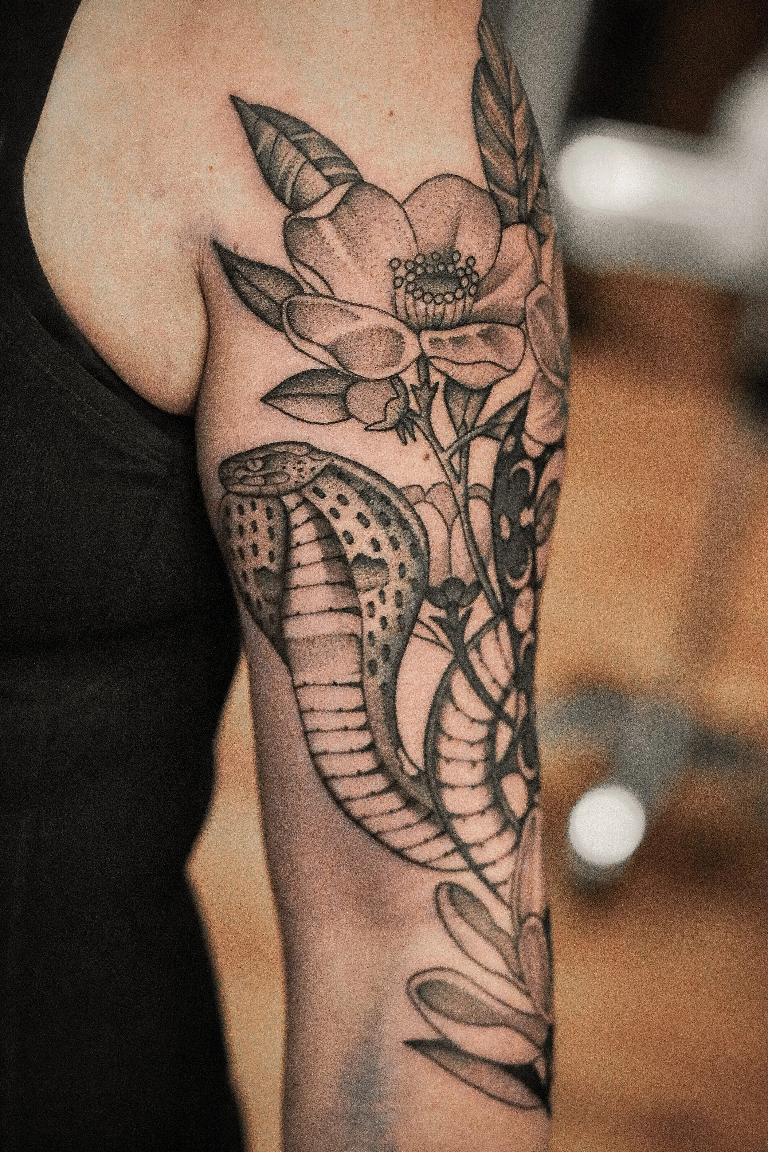 A tattoo of a dragon with detailed scales, wings, and a long, curved tail, covering a person's arm.