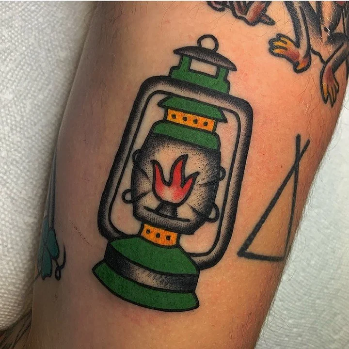 Tattoo of a vintage green lantern with a small red flame inside.