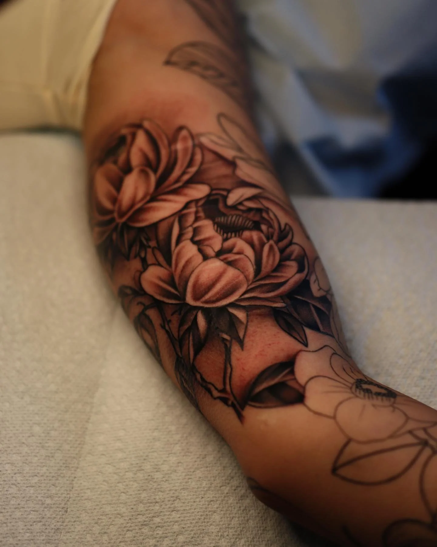 Close-up of a forearm with a detailed black and gray floral tattoo.