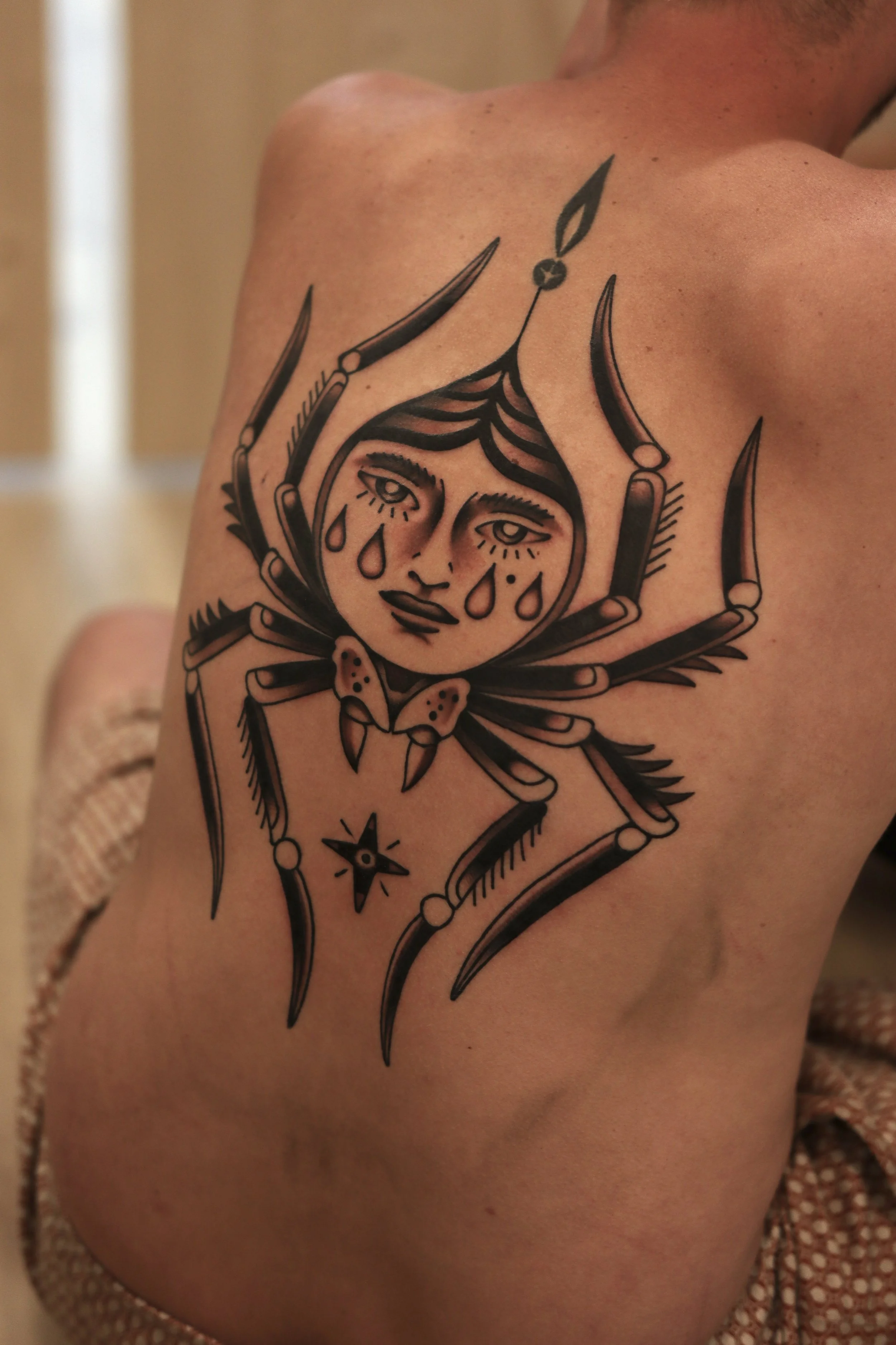 Tattoo of a woman with tears on her face within a geometric design on a person's arm.