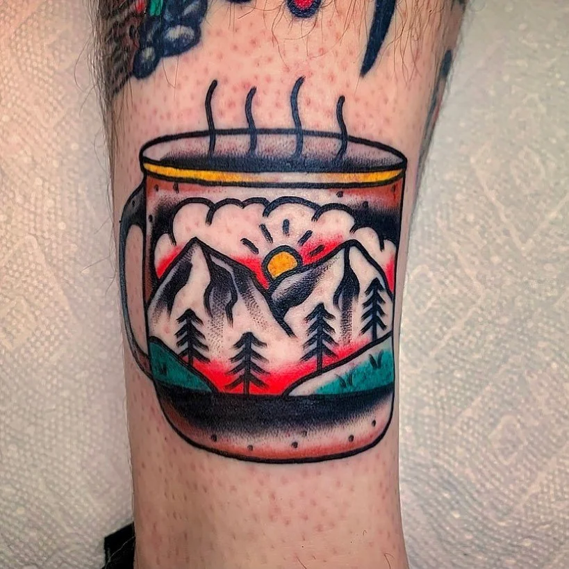 Tattoo of a mountain landscape inside a steaming mug.