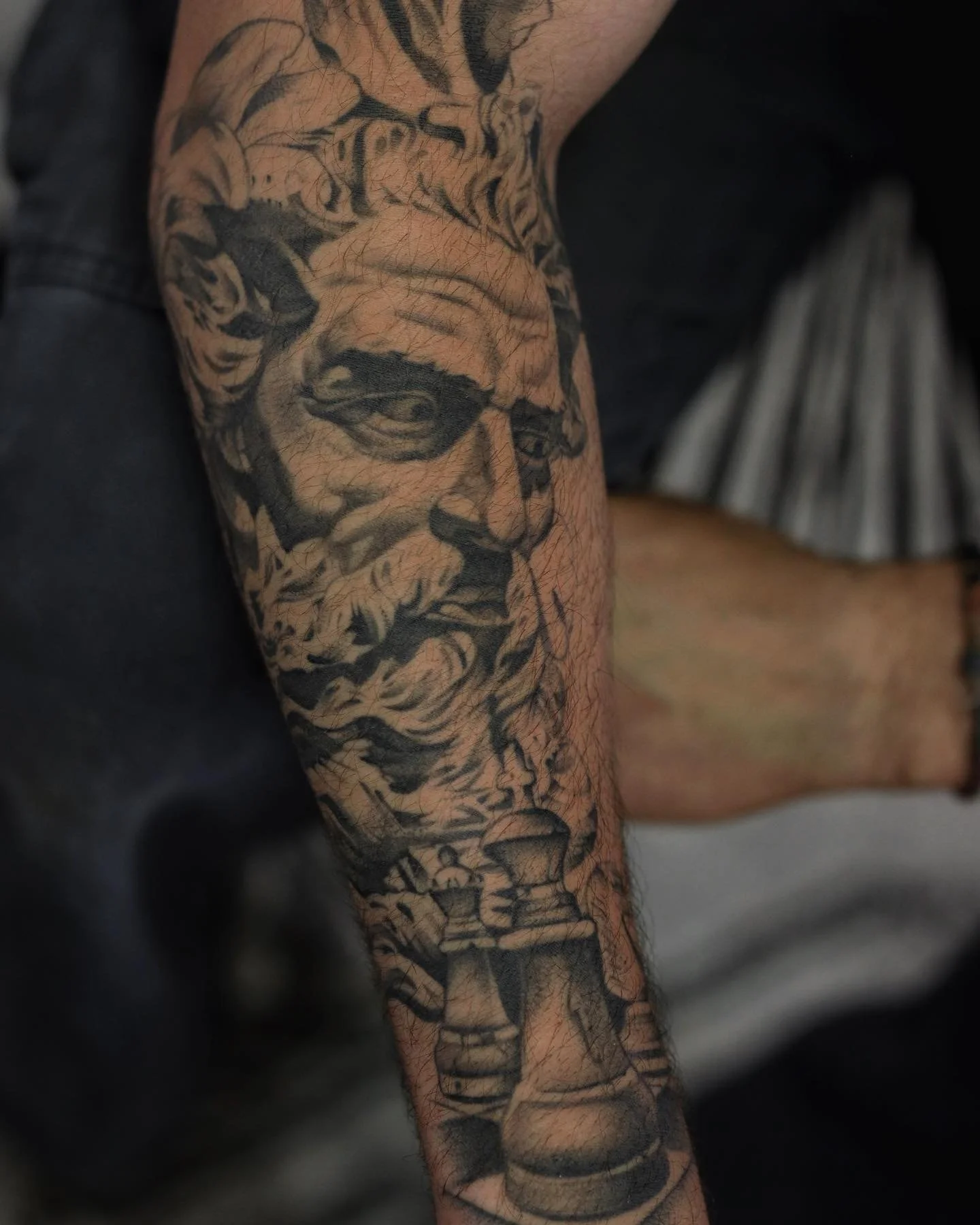 Tattooed arm with sketches of a woman's face, numerous lines, and abstract designs.