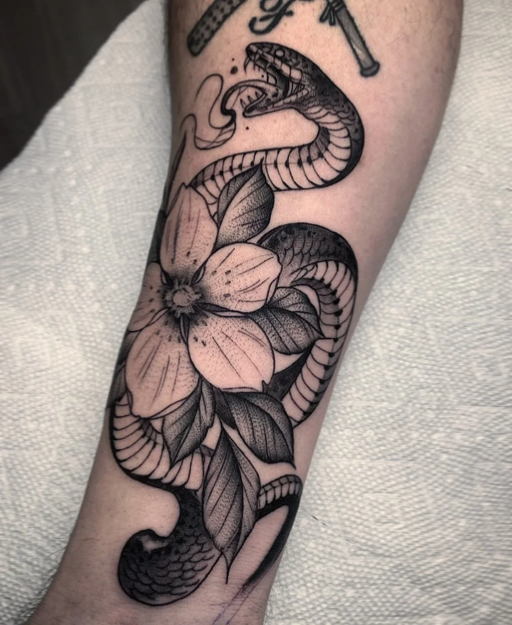 Tattoo of a snake intertwined with a flower on a person's forearm.
