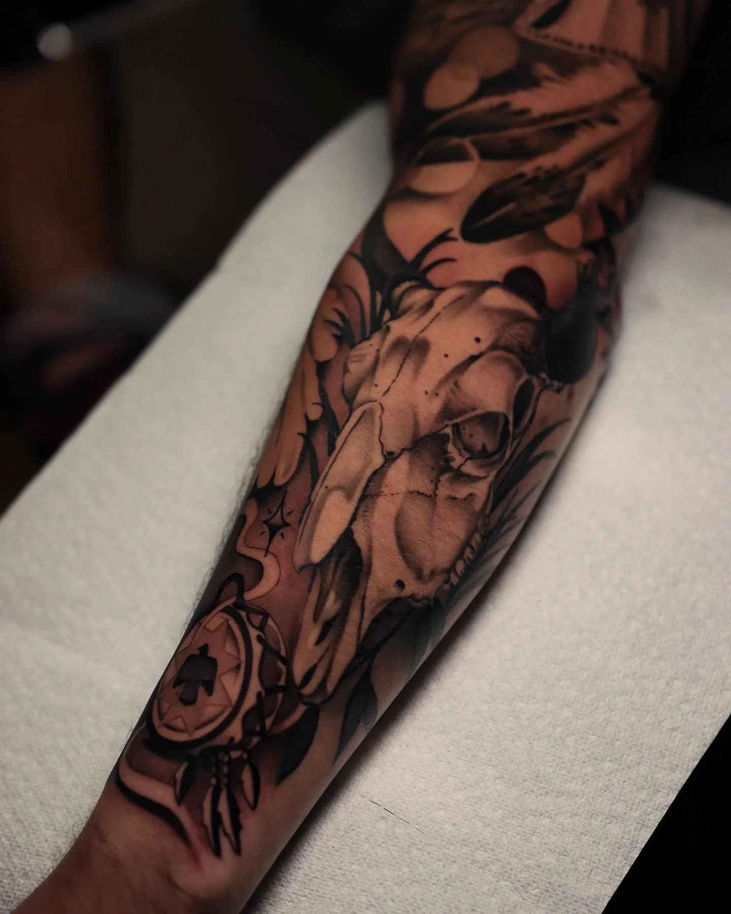 Close-up of a person's arm with a colorful tattoo sleeve featuring floral and abstract designs.
