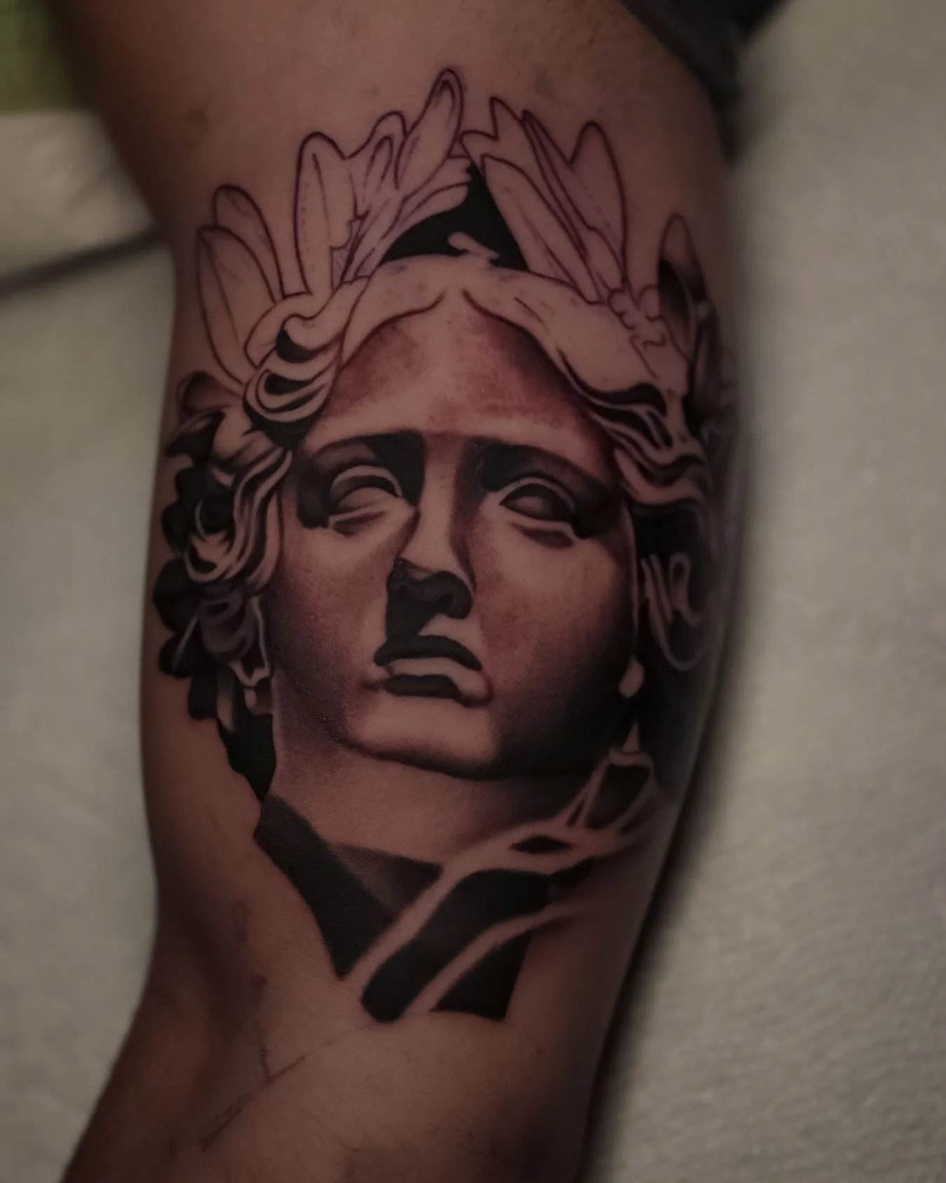 Tattoo of a classical woman's bust with detailed curly hair and a serious expression.