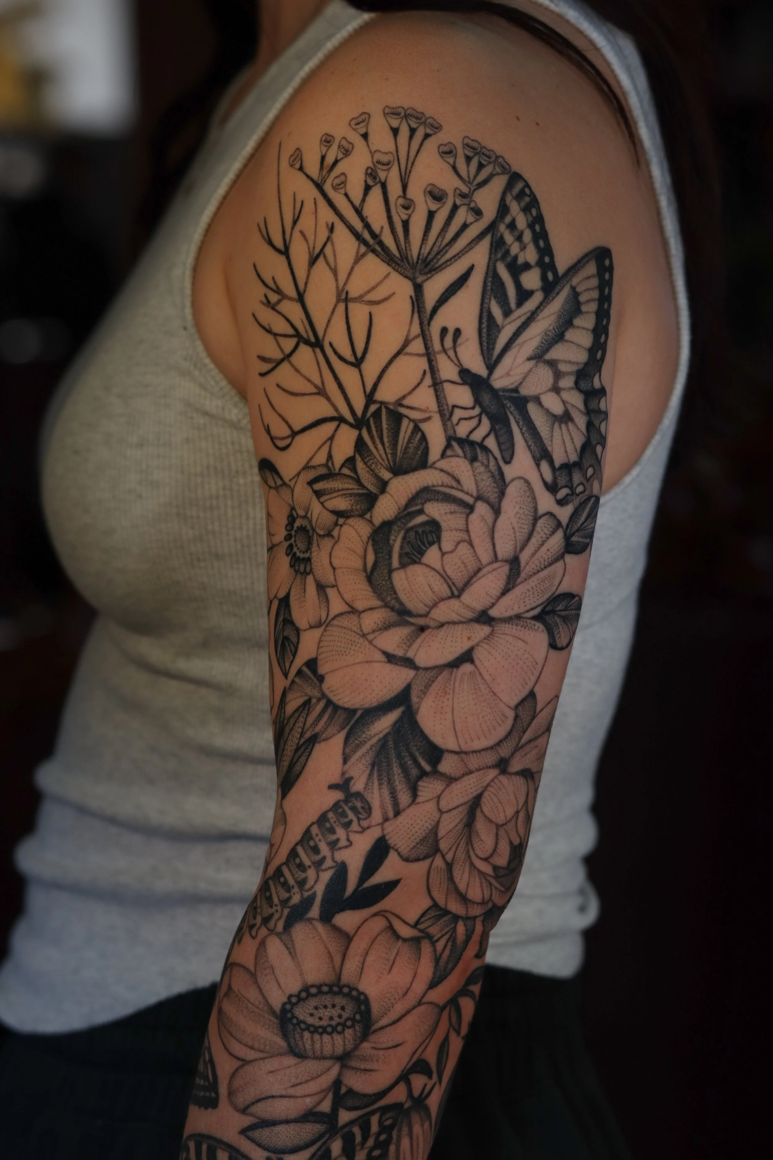 Black ink floral tattoo sleeve featuring various flowers and a butterfly.