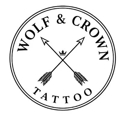Logo for Wolf & Crown Tattoo featuring crossed arrows and a crown in the center, with the text 'WOLF & CROWN TATTOO' around the circle.