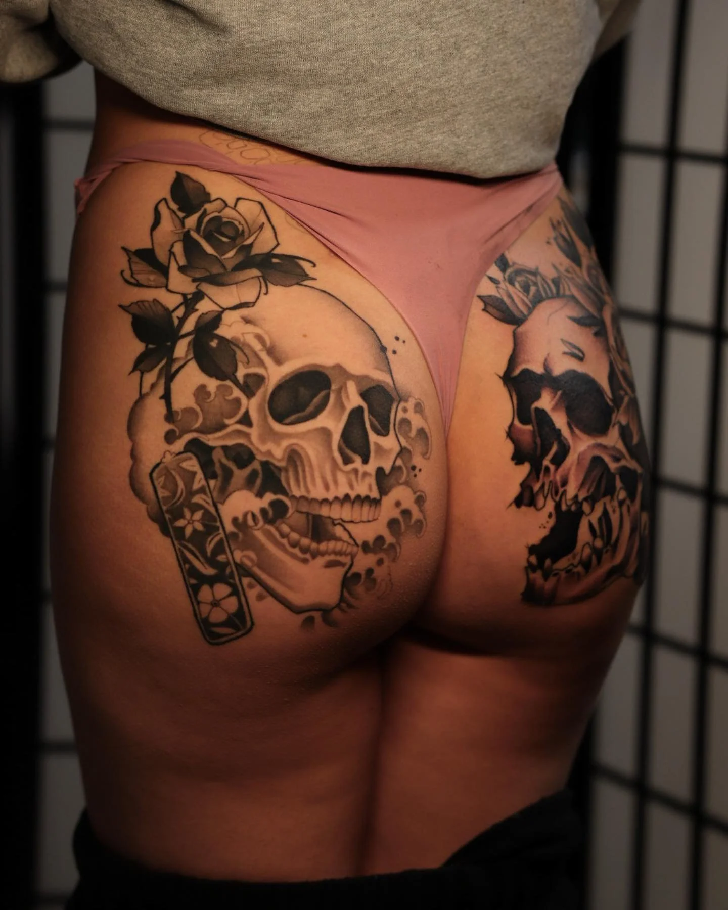 Tattoo of a skull with roses and a tiger on a person's thigh and buttock.