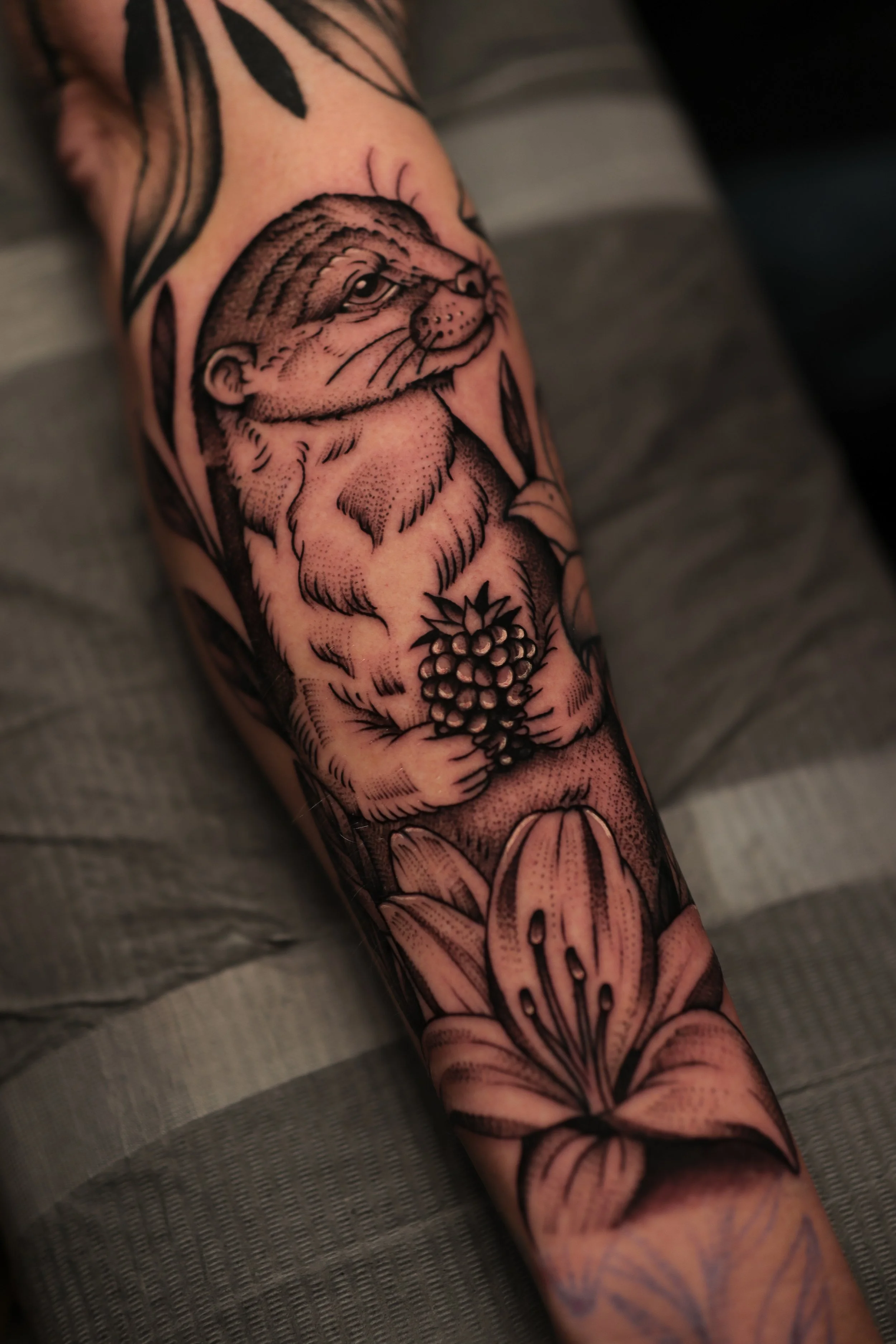 Tattoo of a lion's face on a person's arm, with roses and other floral designs around it.