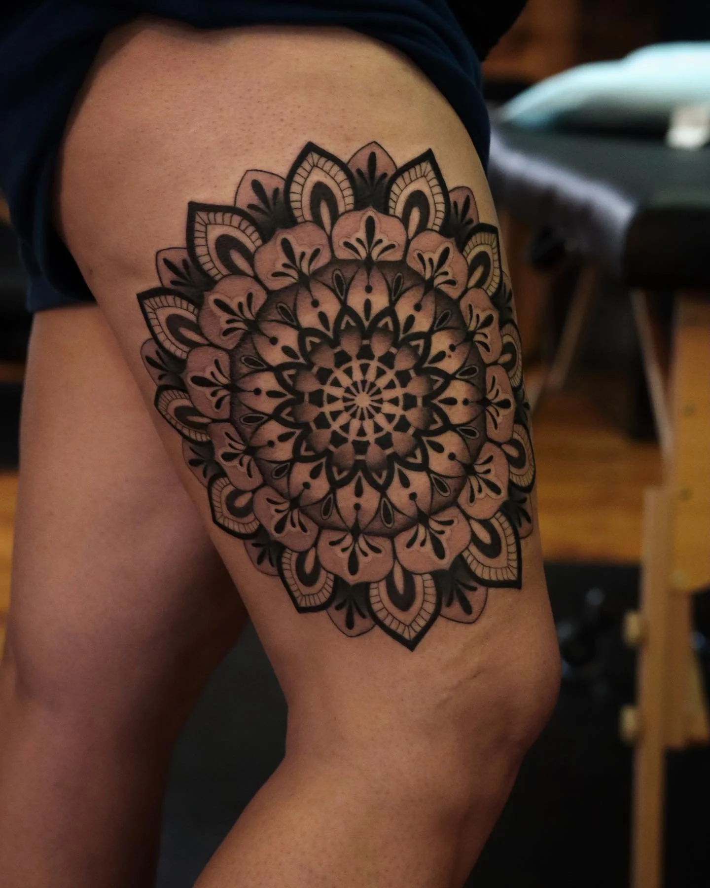 Black and gray mandala tattoo on person's thigh.