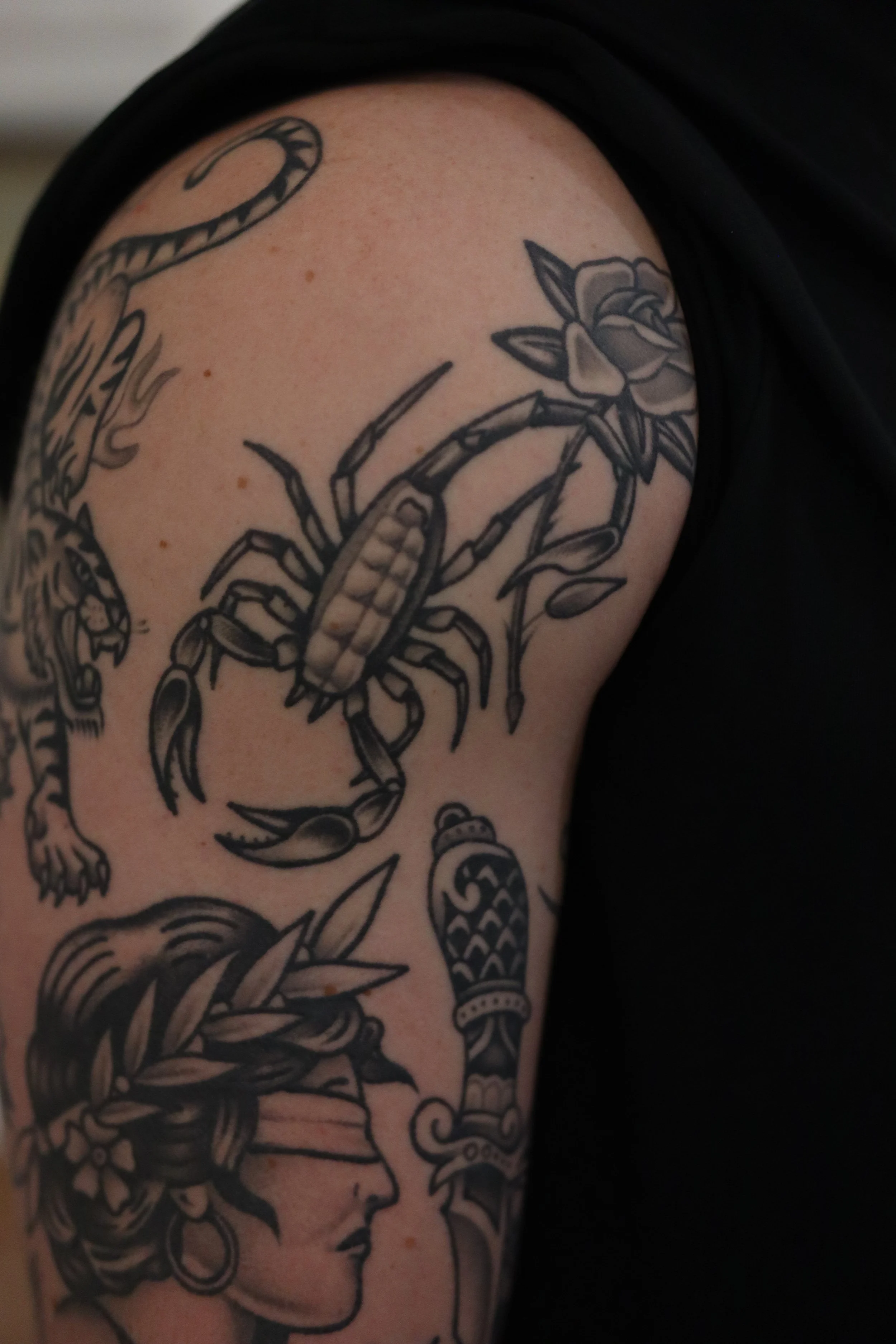 Tattoo of a woman with flowing hair and a flower on the shoulder.