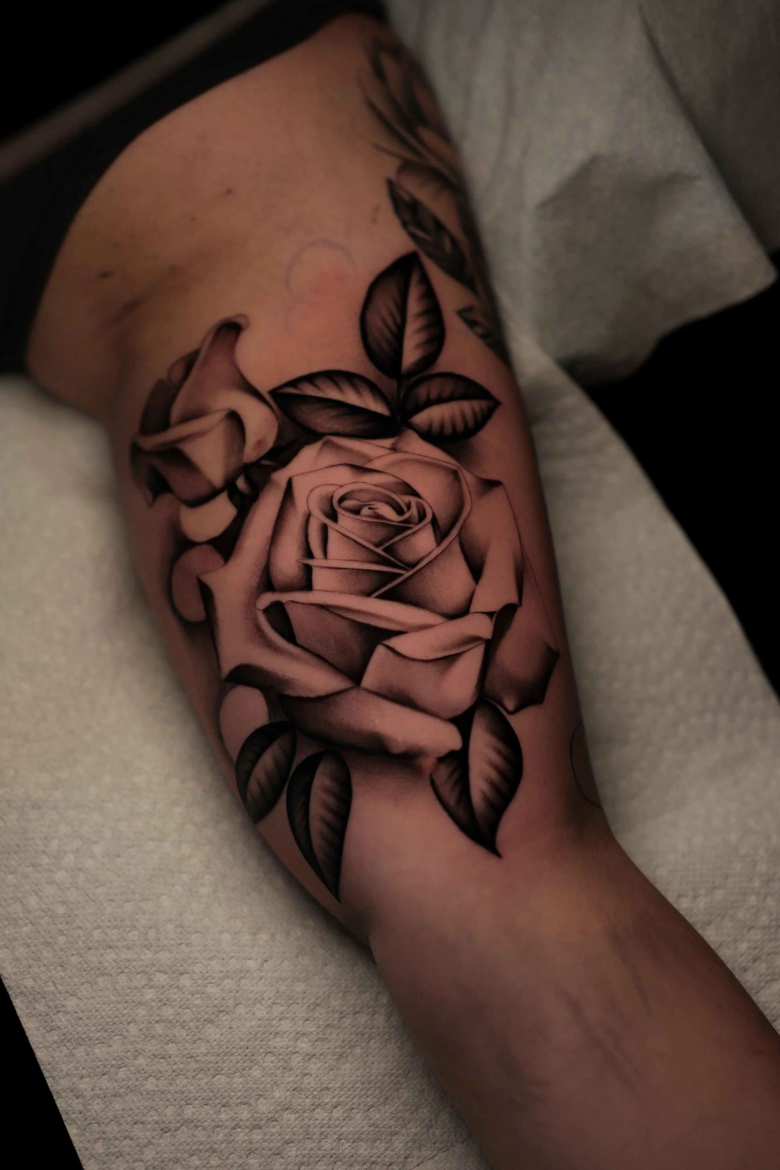 A tattoo of a bouquet of roses and leaves on a person's arm.