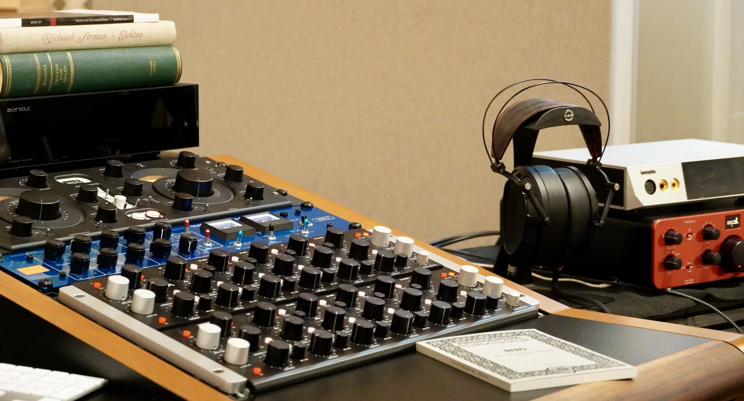 Musik-Equipment auf einem Tisch, einschließlich Mixer, Kopfhörer, Audio-Interface und mehreren Partituren.