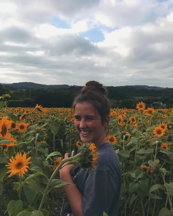 Mia (artist) smiling in a sunflower field