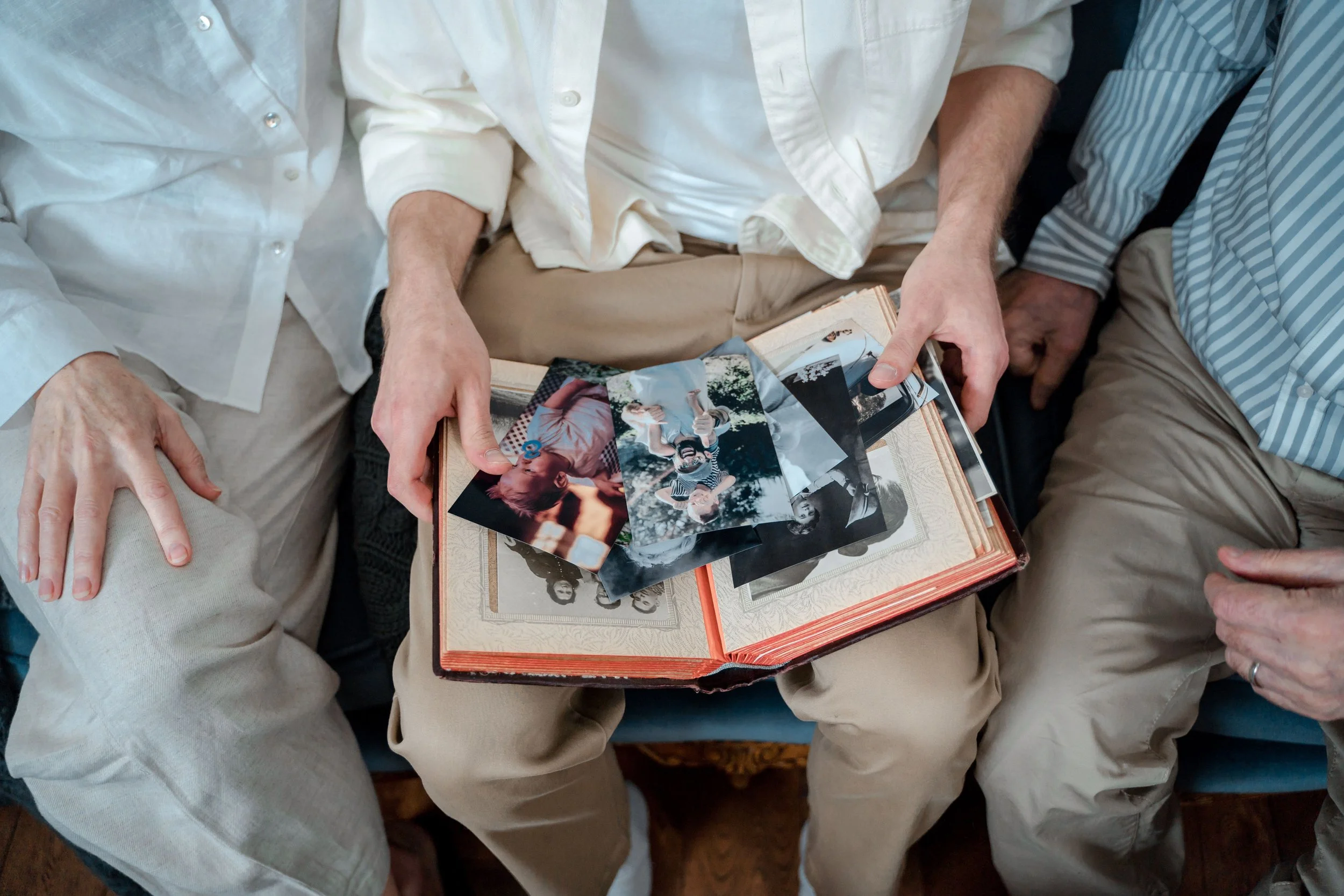 A family of three enjoying old photos together, sharing cherished memories.