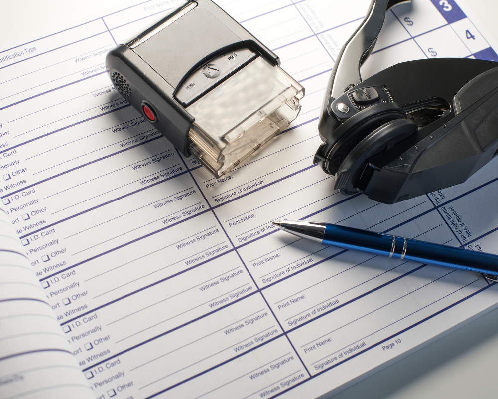 Documents with check boxes and lines for signatures, a pen, a wristwatch, and a voice recorder on top.