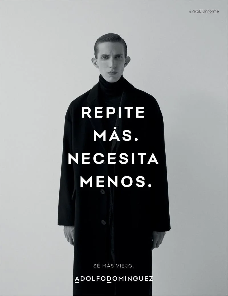 Una persona con ropa oscura mira directamente a la cámara en un fondo gris. El texto en la imagen dice 'Repite más. Necesita menos.' y en la parte inferior, 'Sé más viejo.' seguido del nombre 'Adolfodominguez'.