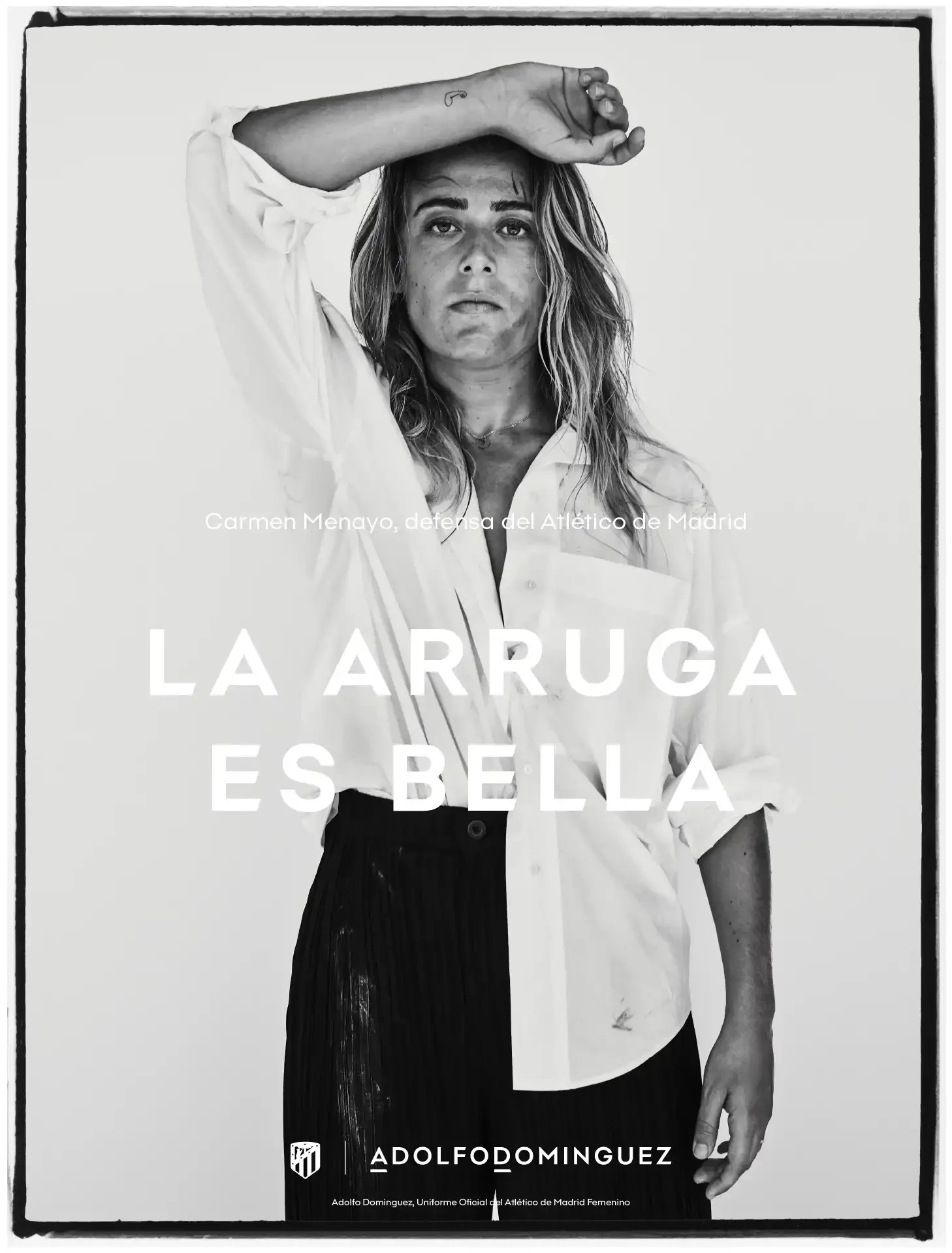 Portada en blanco y negro con una mujer rubia con cabello suelto, con la mano derecha sobre su frente, luciendo una expresión seria. Usa camisa blanca y falda negra. Texto en la portada: 'La arruga es bella', presenta el nombre Adolfo Domínguez, y un