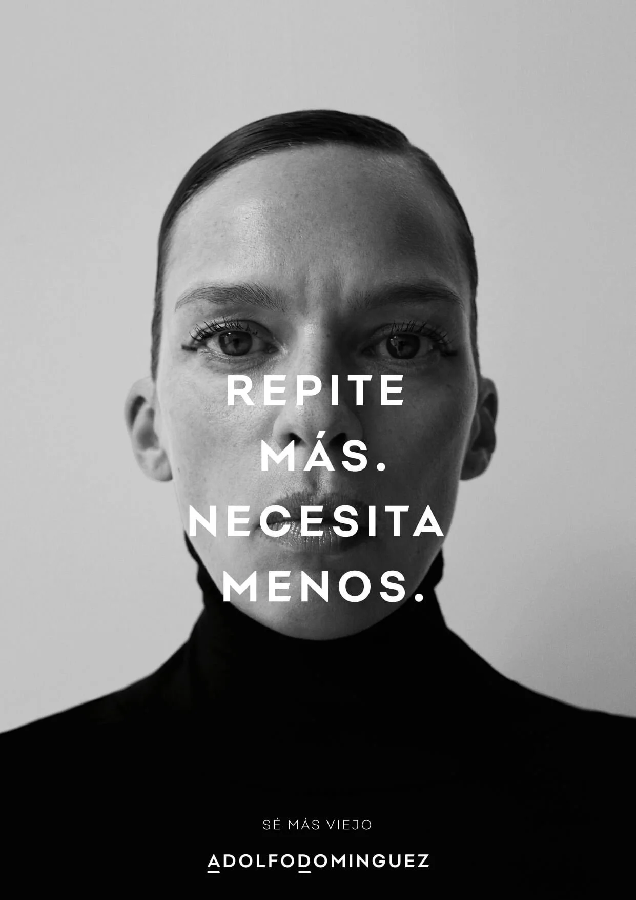Retrato en blanco y negro de una mujer con cabello de corte corto y cejas arqueadas, mirando directamente a la cámara. Texto superpuesto en el centro que dice 'Repite más. Necesita menos.'. Abajo, en la parte inferior de la imagen, texto que dice 'Sé más viejo' y la firma 'Adolfodominguez'.