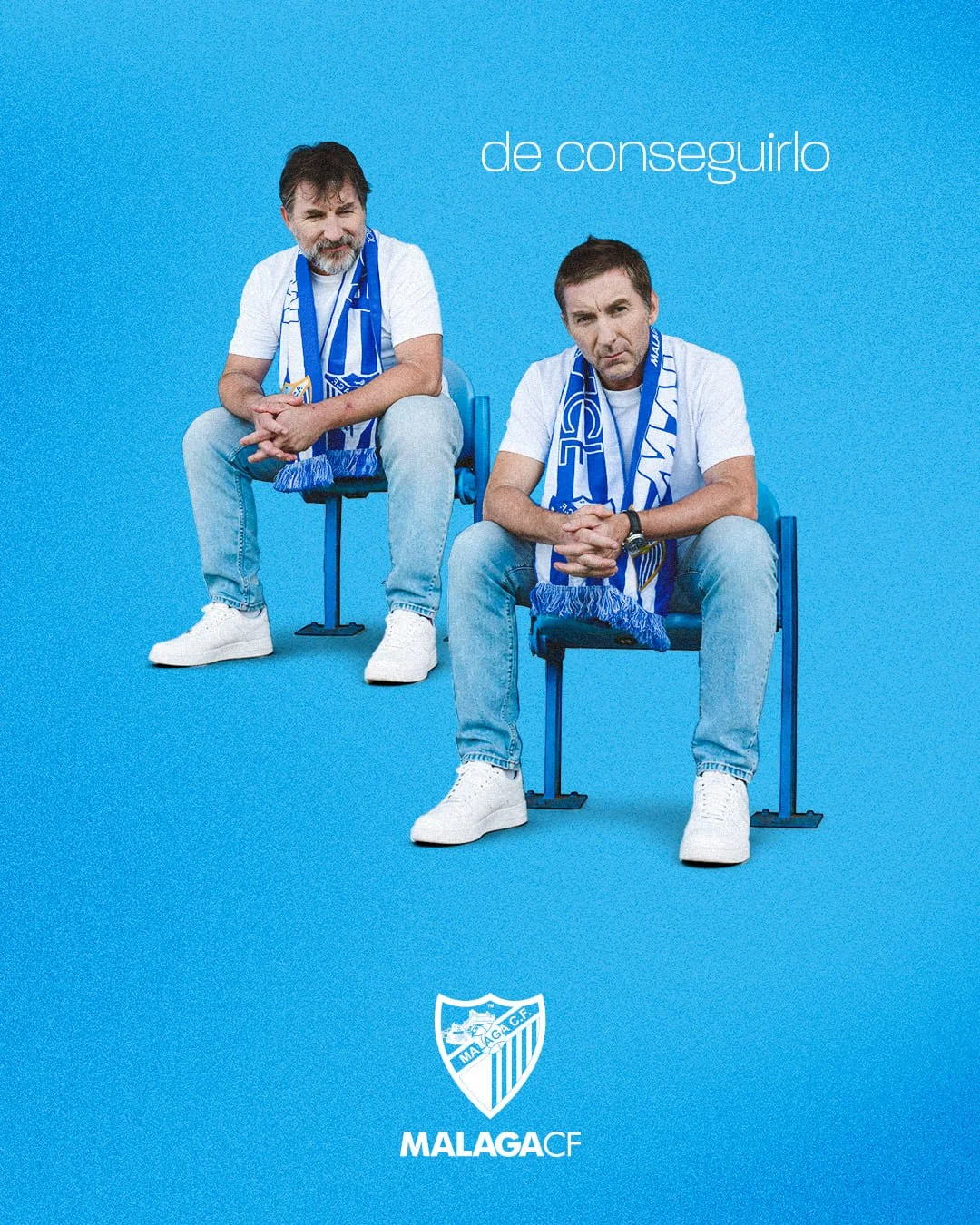 Dos hombres sentados en sillas, con camisetas blancas y bufandas del equipo de fútbol Málaga CF, sobre un fondo azul. Texto en la imagen: 'de conseguirlo.' Logo del equipo en la parte inferior.