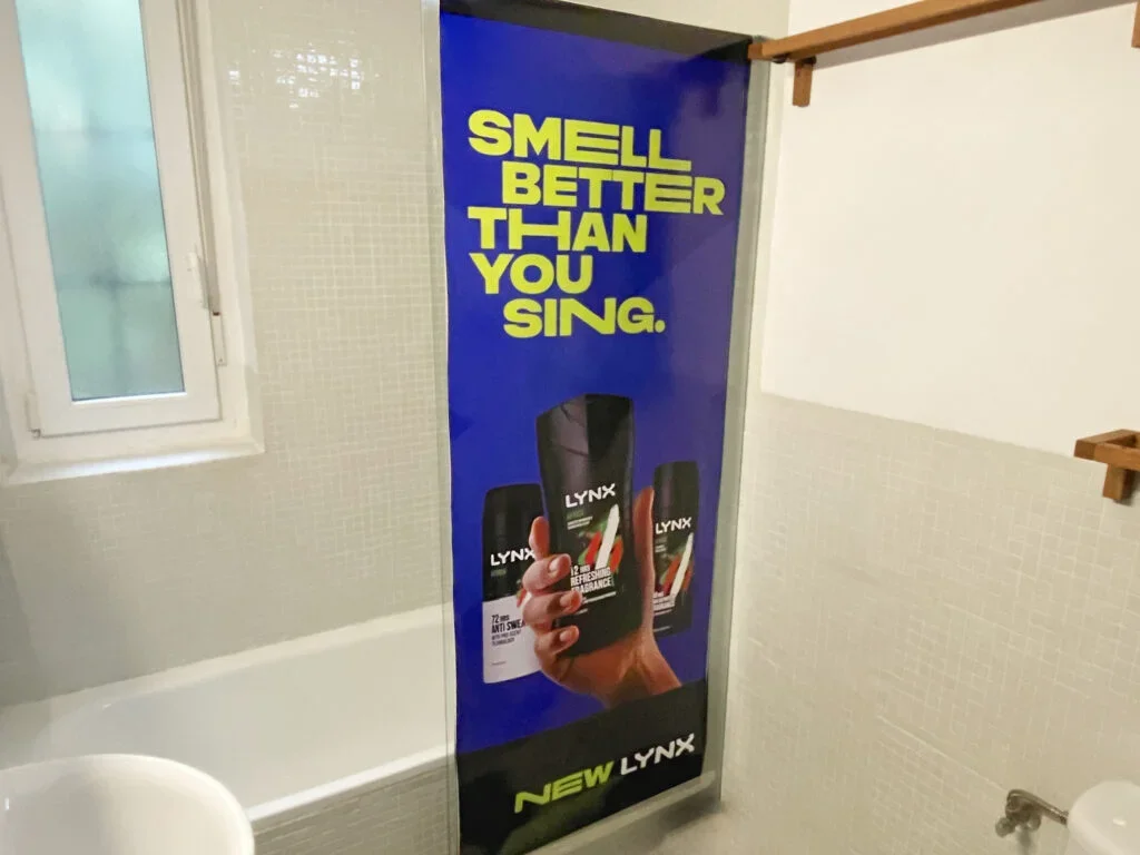 Publicidad en una bañera que dice 'Huele mejor que cantar' y muestra un par de desodorantes Lynx.