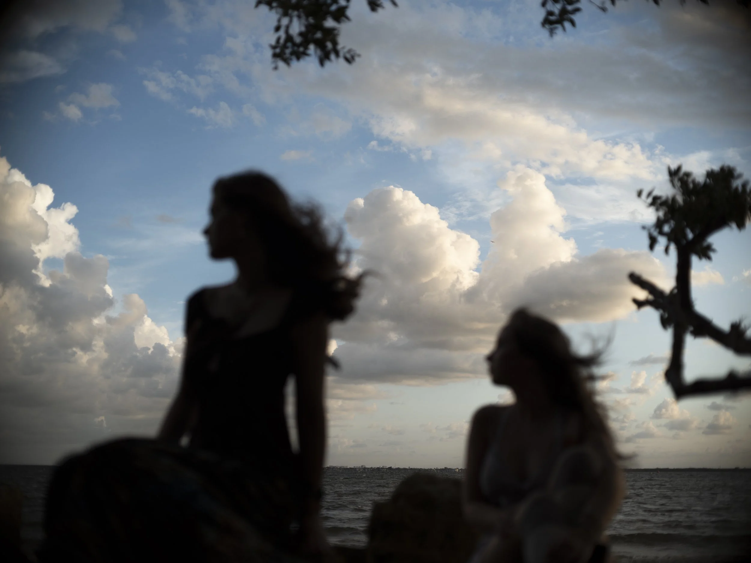 Silhouetted woman outdoors near water with clouds in the sky