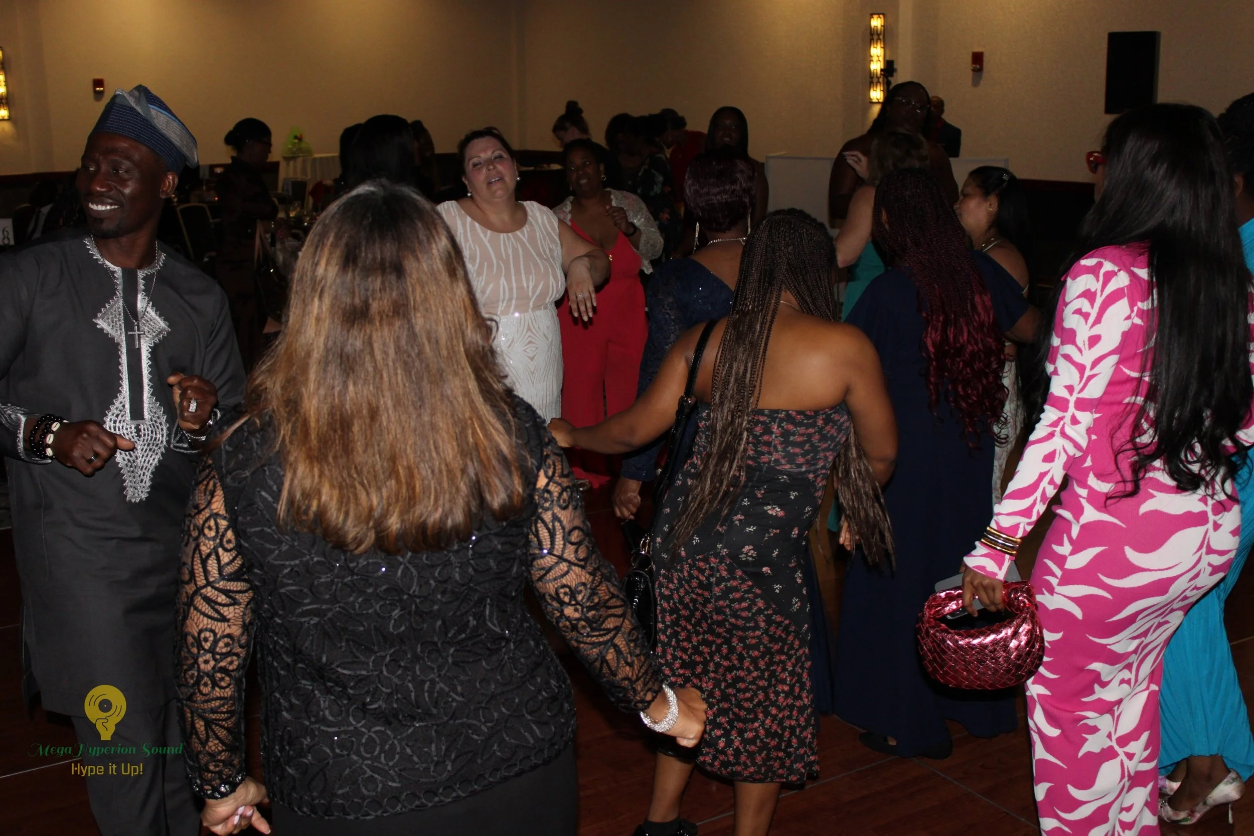 Group of people at a social gathering or party, dancing and chatting in a dimly lit room with elegant decor.