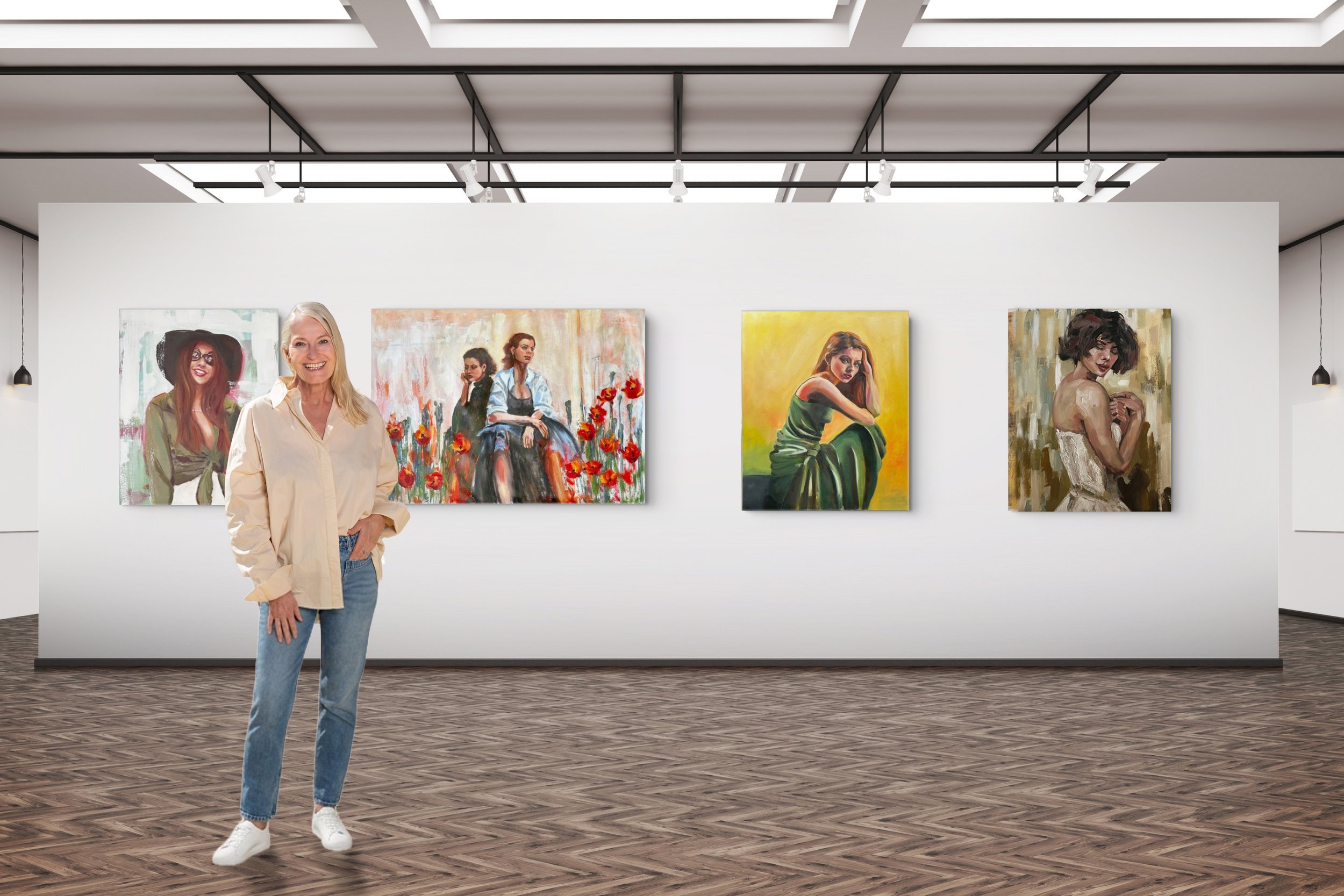 A female artist wearing a yellow shirt and blue jeans standing in an art gallery, smiling at the camera. Behind her, there's a white wall with four colourful portrait paintings of women.