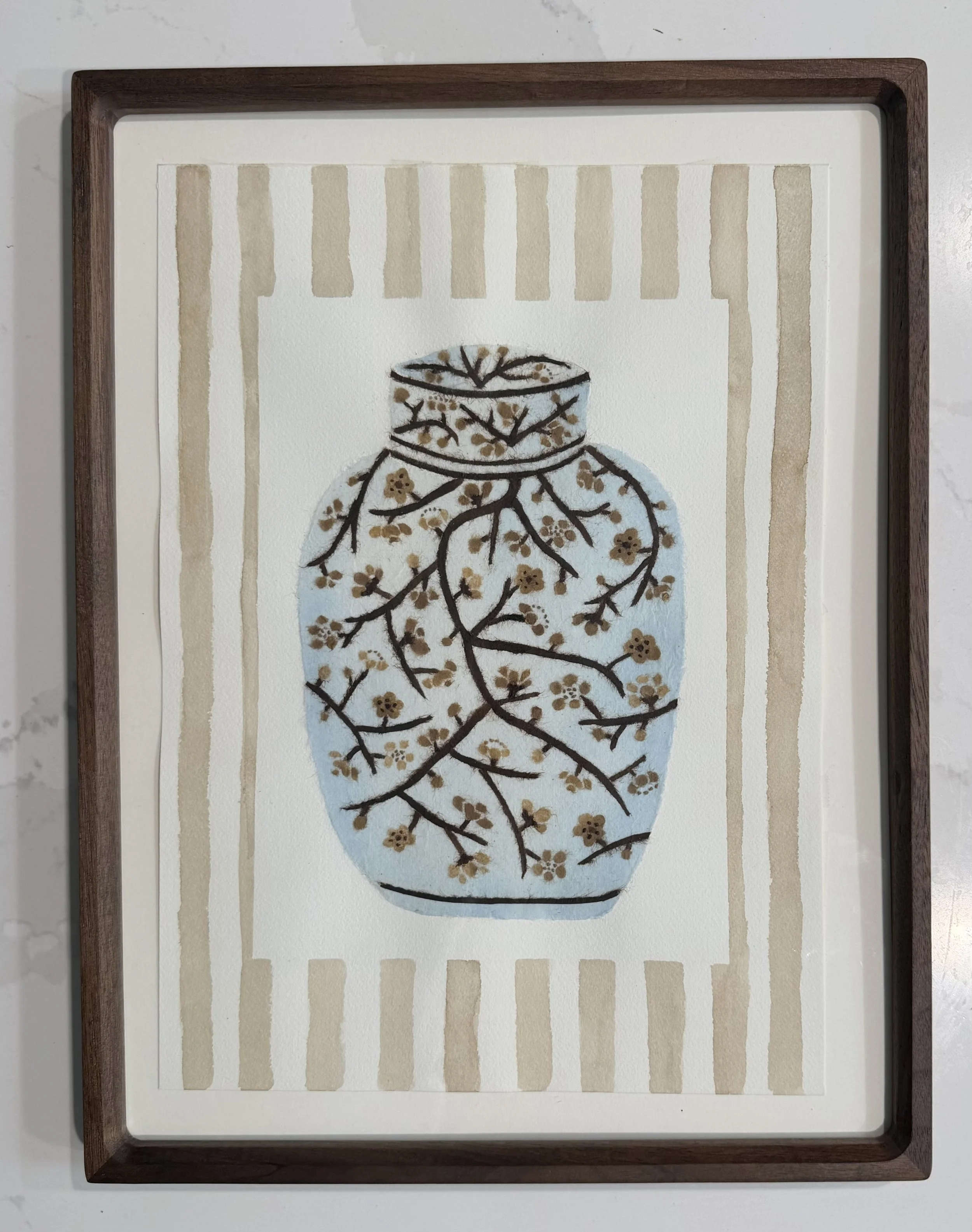 Chigiri-e piece of a ginger jar vase with branches and small flowers in front of a beige and white striped background, framed in a wooden frame.