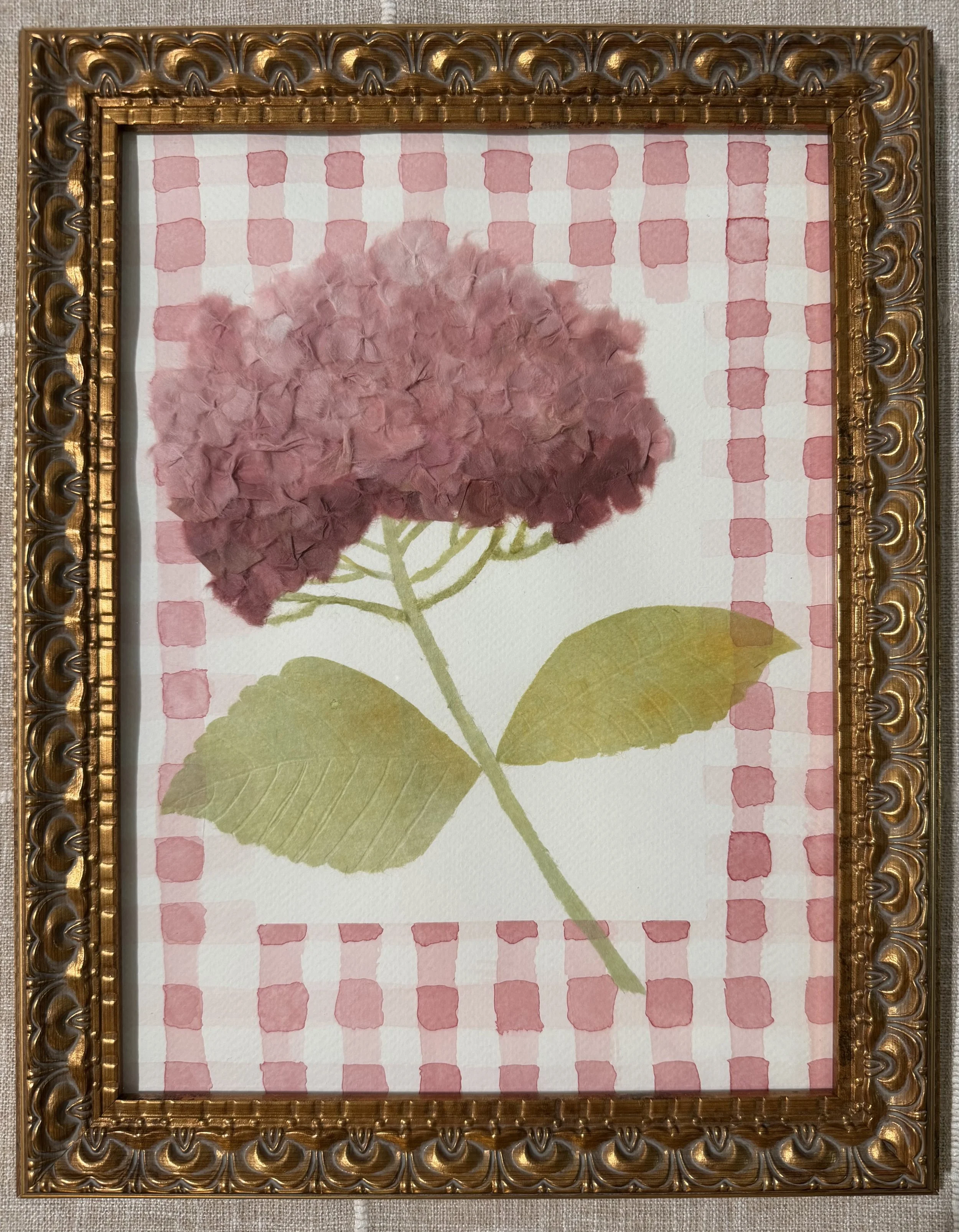 Framed artwork of a pink hydrangea flower with green leaves on a checked pink and white background.