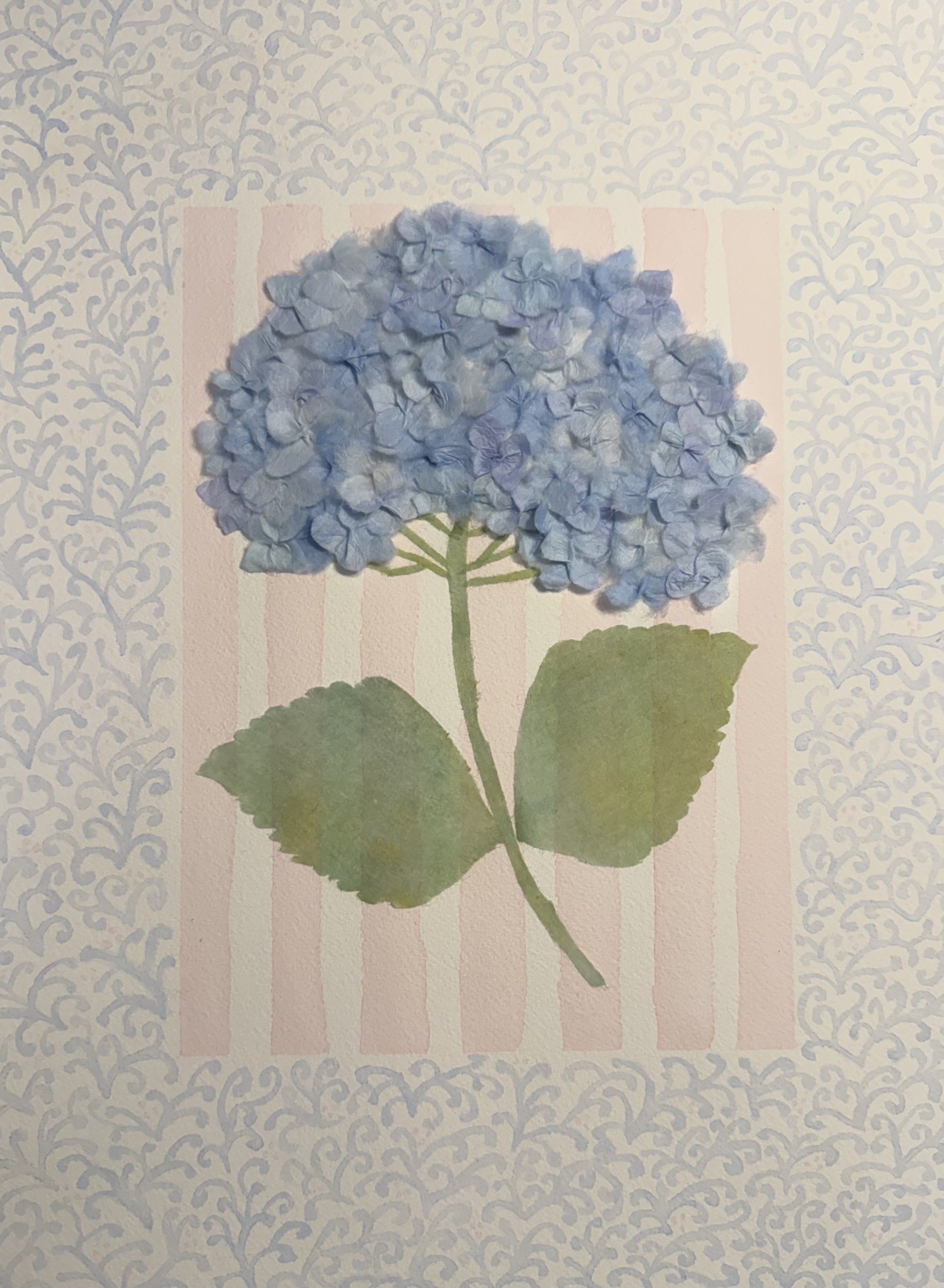 A blue hydrangea flower with green leaves on an attractively patterned background.