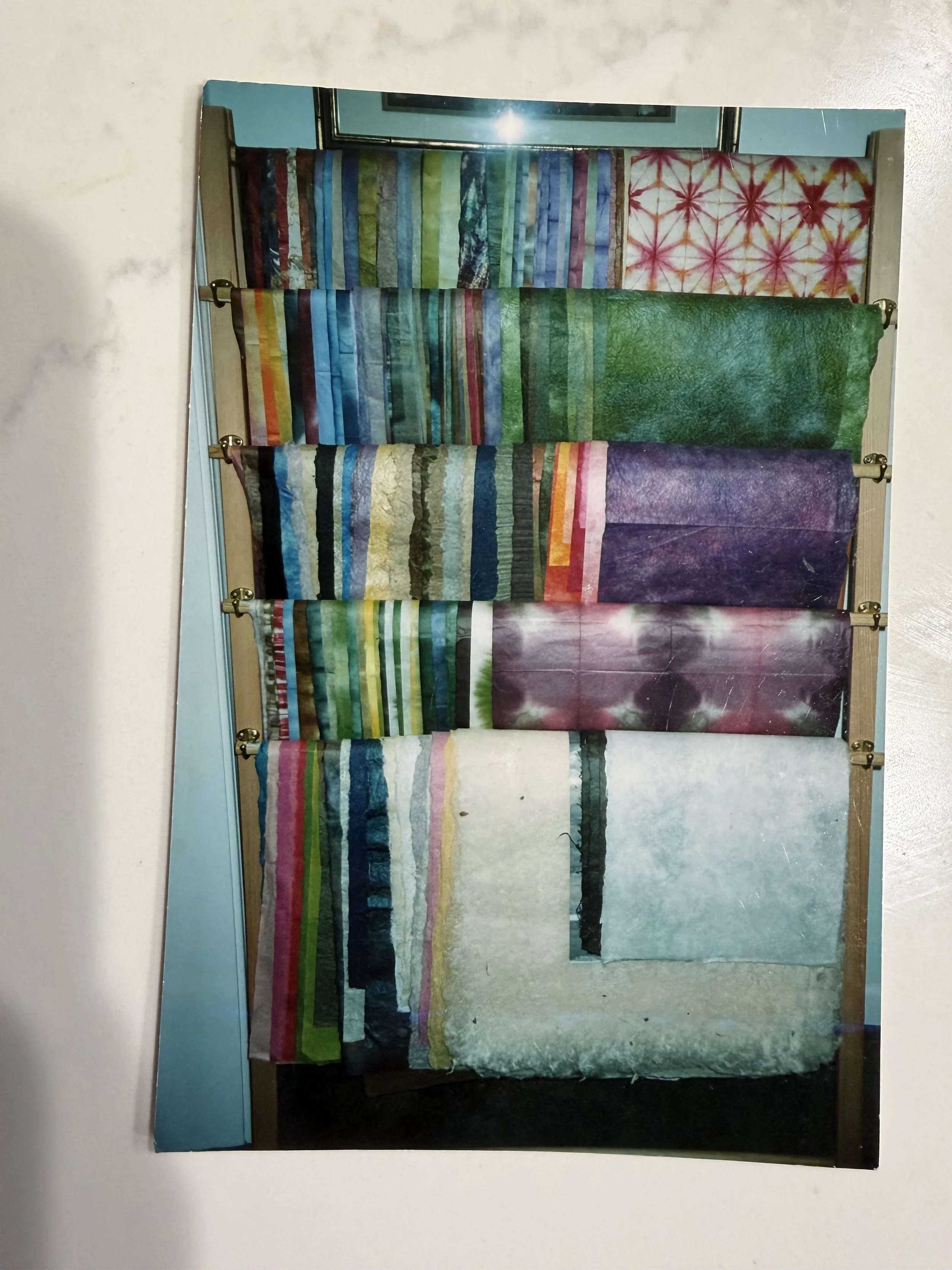 Display of Japanese washi paper in various colors and patterns on a wooden rack.