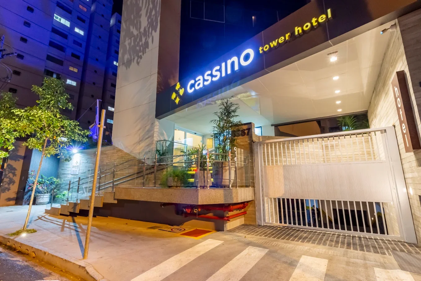 Recepção de hotel com móveis de madeira, um balcão de check-in, estantes com livros, menu de arte na parede, poltronas de madeira, uma mesa de centro de madeira, refrigeradores de bebidas, e decoração moderna.