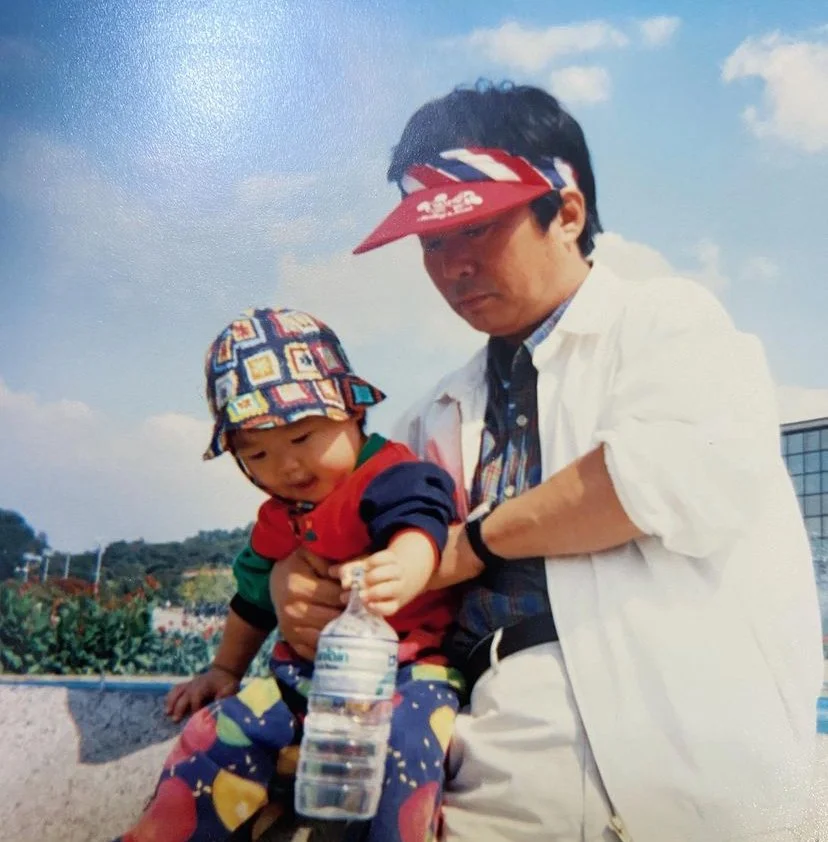 Jiggy Yoon as a child being held by her father outdoors