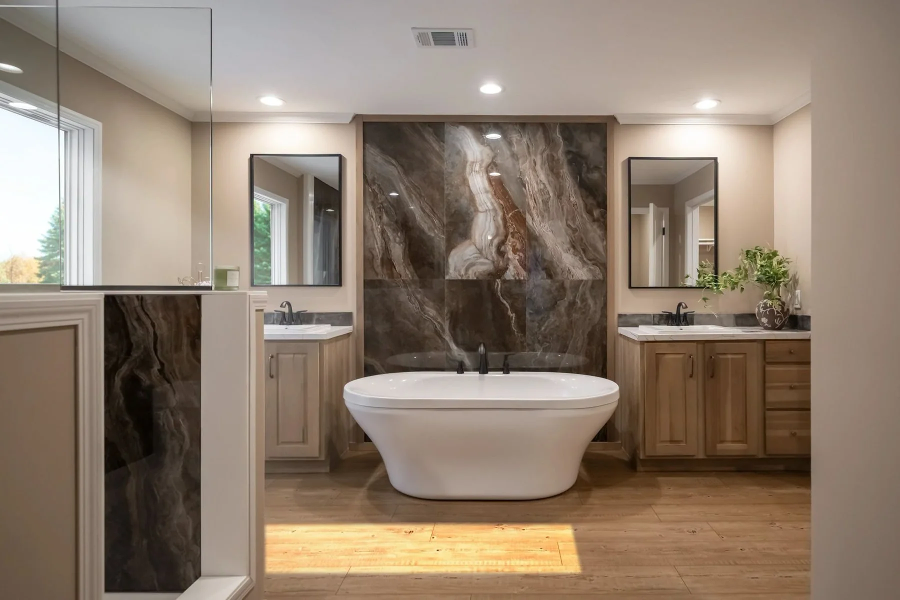 Modern bathroom with a freestanding bathtub, dual sinks, large mirror, natural wood cabinets, marble accents, potted plant, and windows with outdoor view