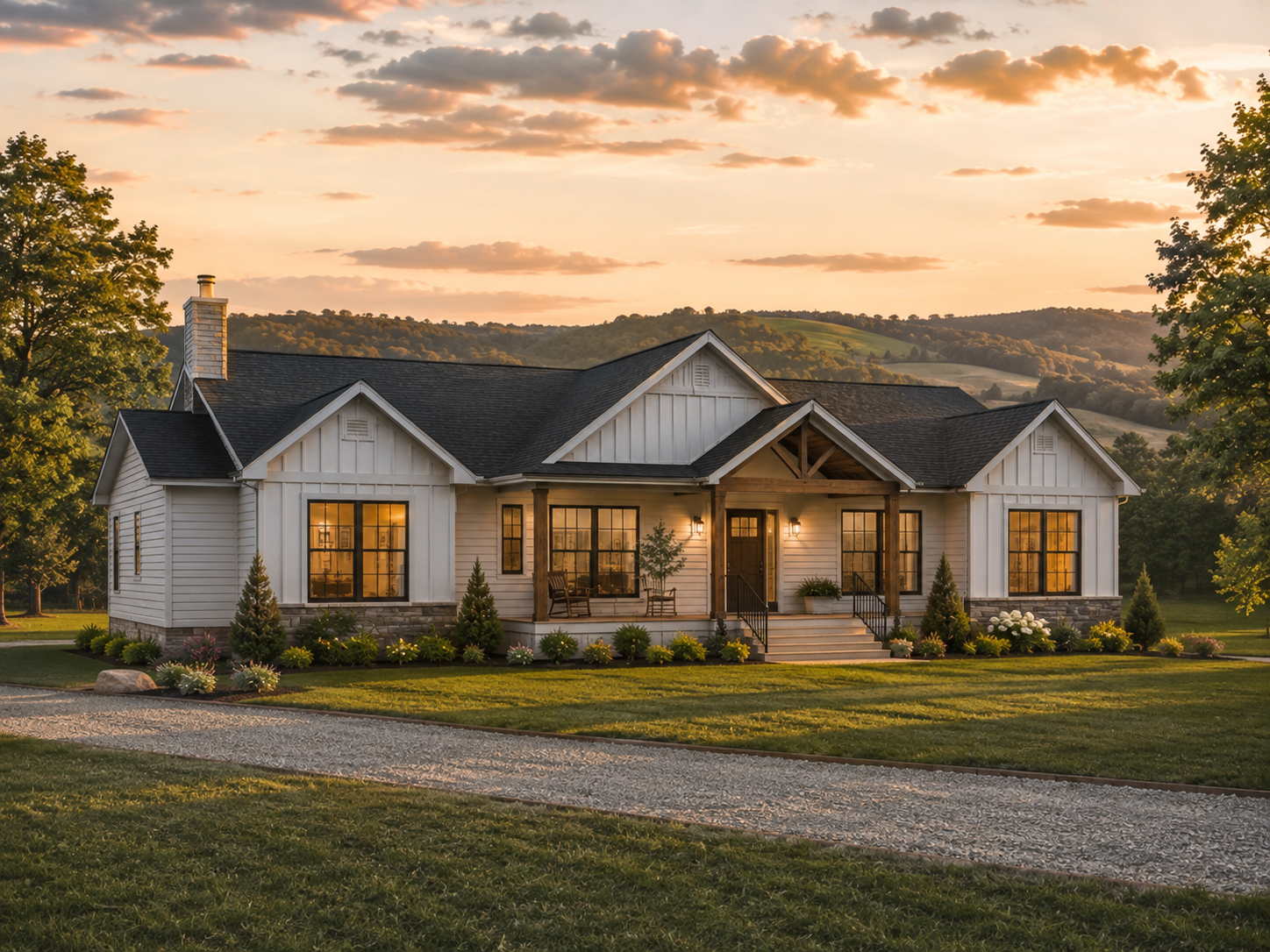 A beautiful house with white exterior walls and large front windows, situated in a lush green landscape with trees and rolling hills in the background, under a sunset sky.