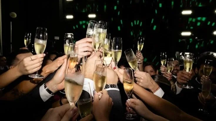 Group of people holding champagne glasses in a celebratory toast at a party or event.