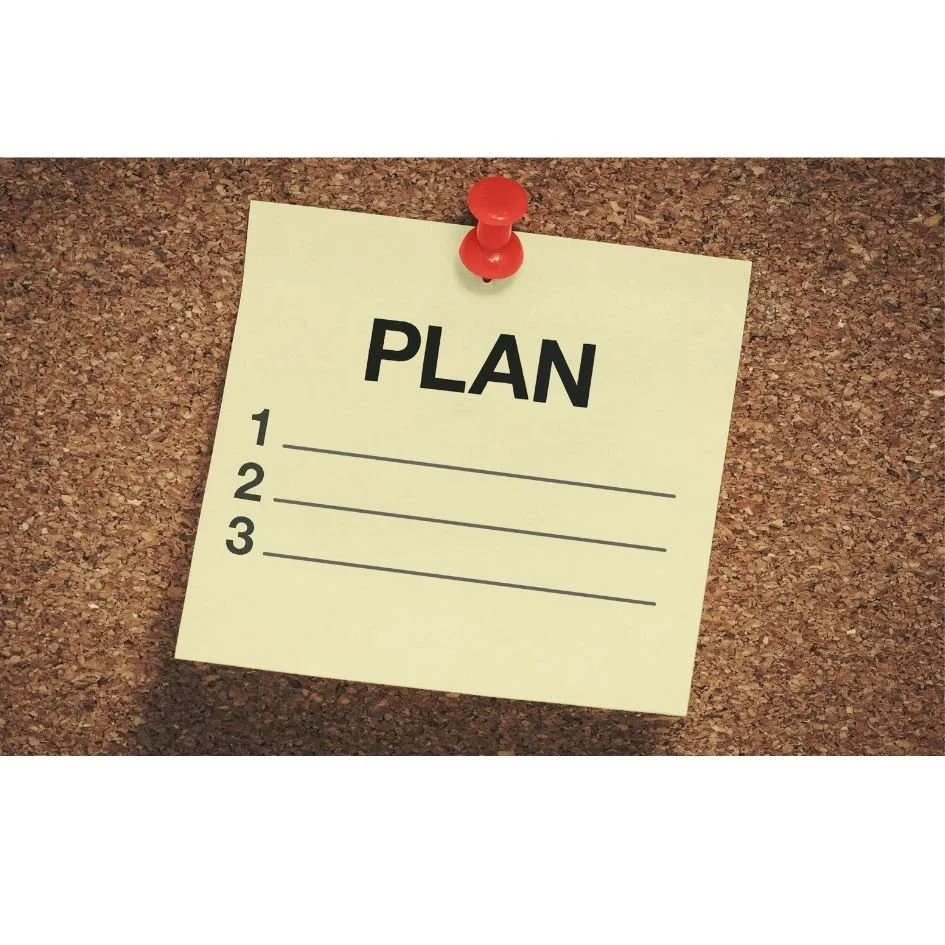 Eine Notiz mit dem Wort 'PLAN' an einer Pinnwand, mit drei nummerierten Zeilen für eine To-Do-Liste.
