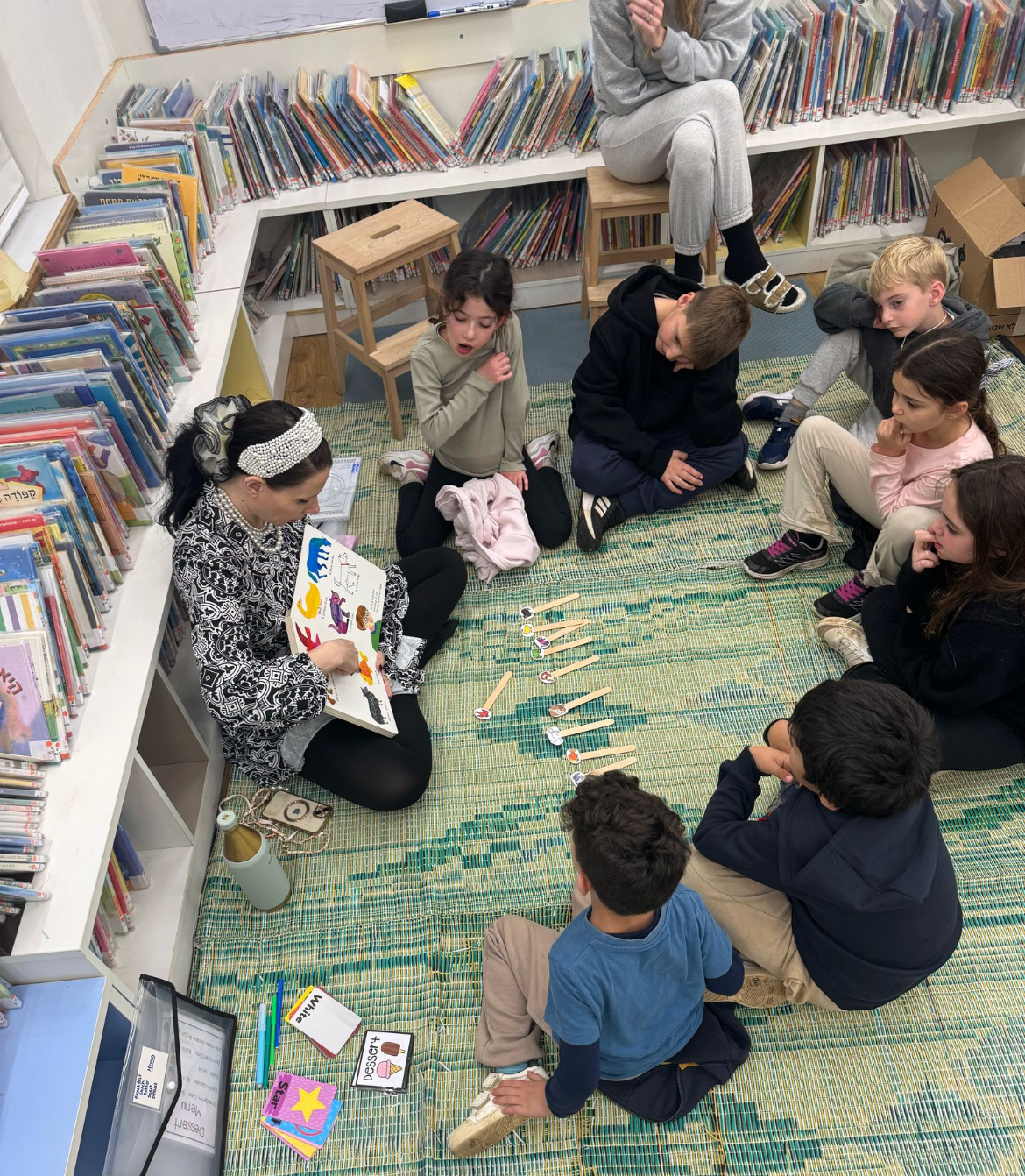 A group of young children working together at a round table in a sunlit school library