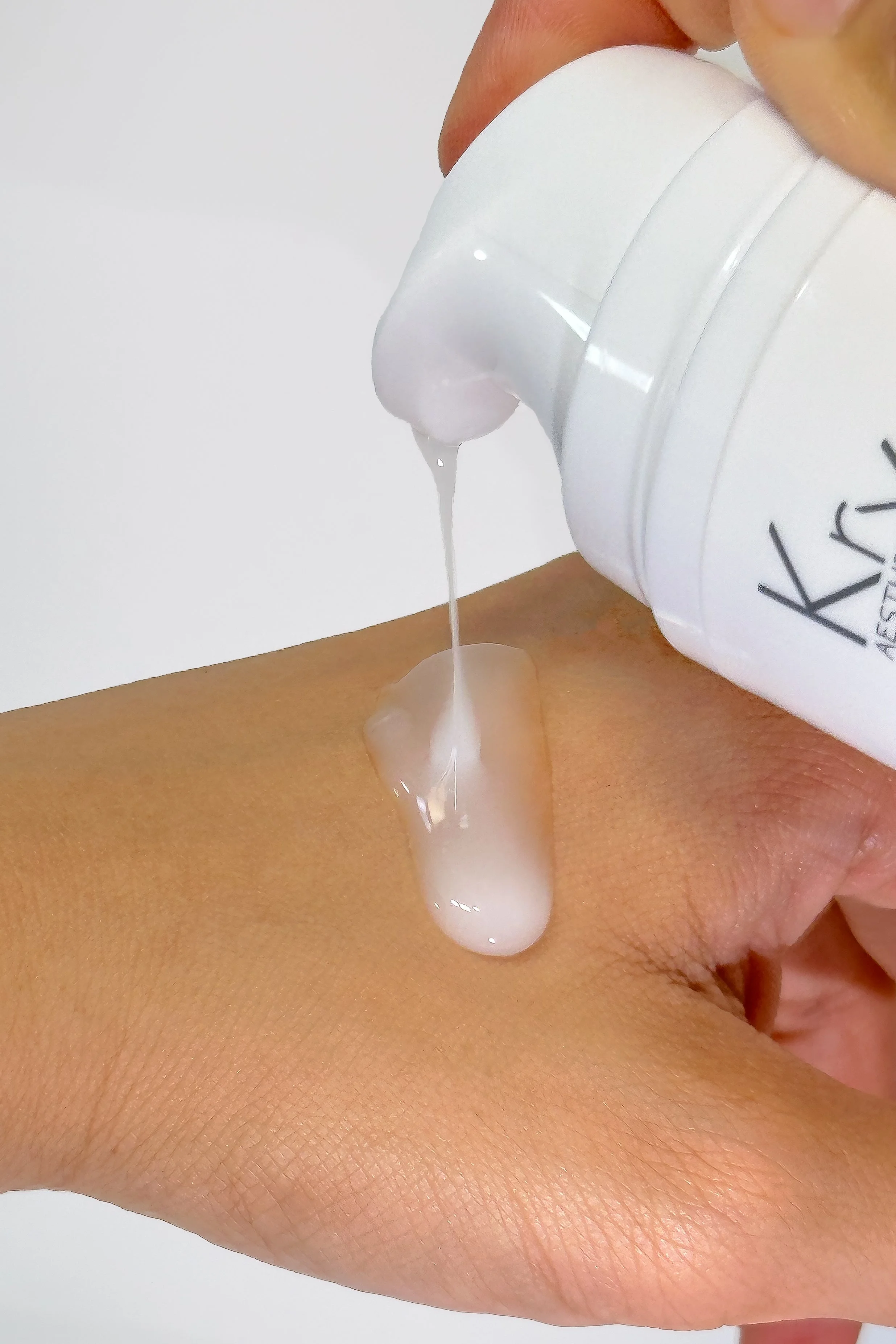 A bottle of white lotion being poured onto a person's back.