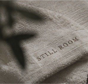A close-up of a cloth with the words 'STILL ROOM' printed on it.