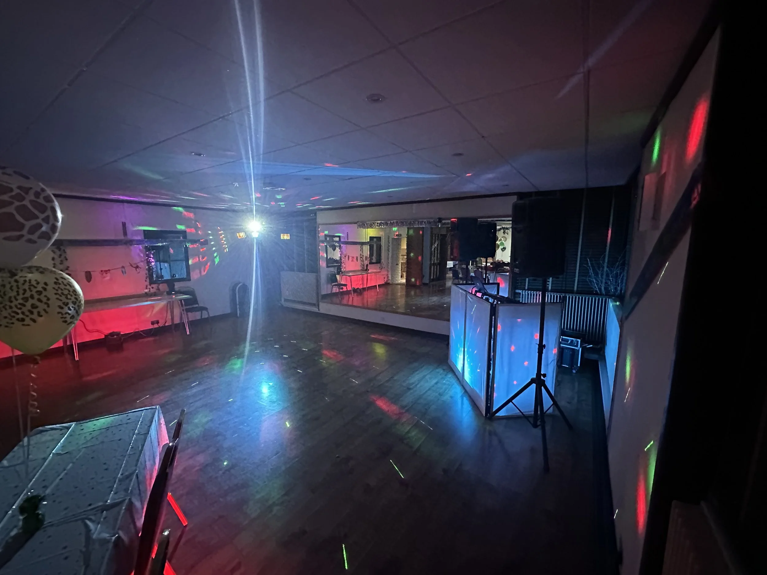 Empty dance floor with colorful lights and disco effects in a club or party venue.