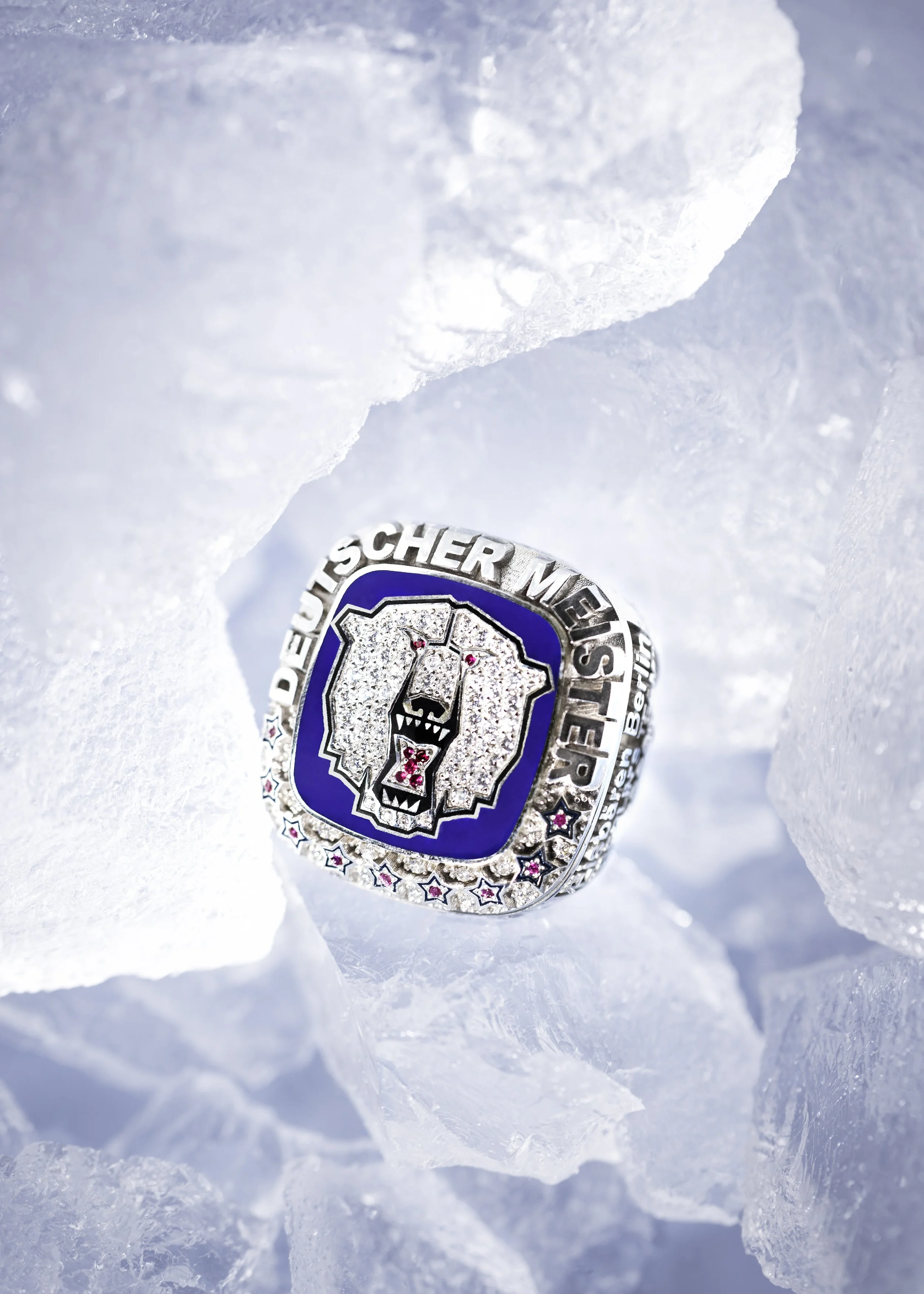 A close-up of a championship ring with diamond details, partially embedded in snow or ice.