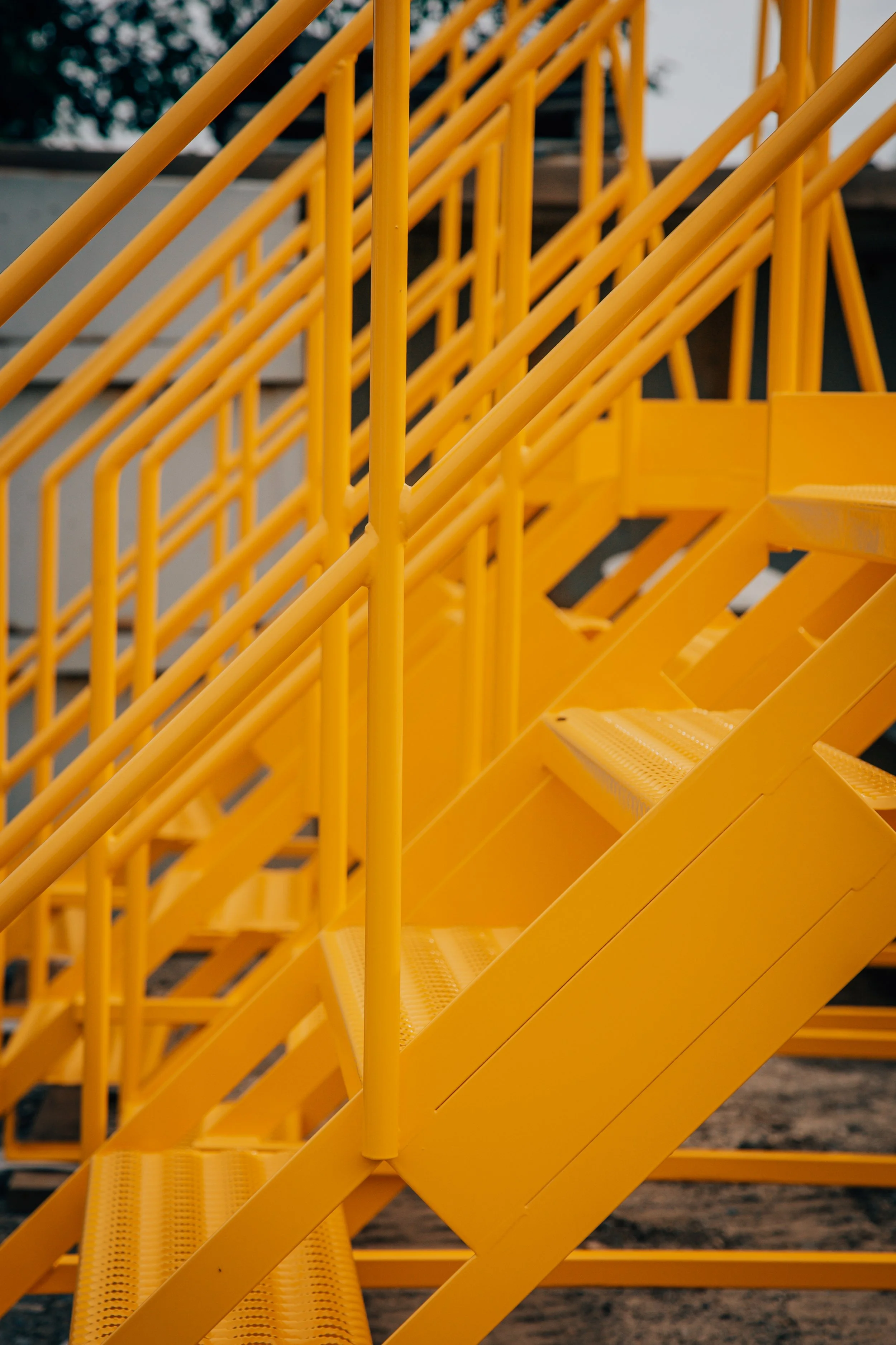 Close-up of yellow metal stairs and handrails at an outdoor construction site.