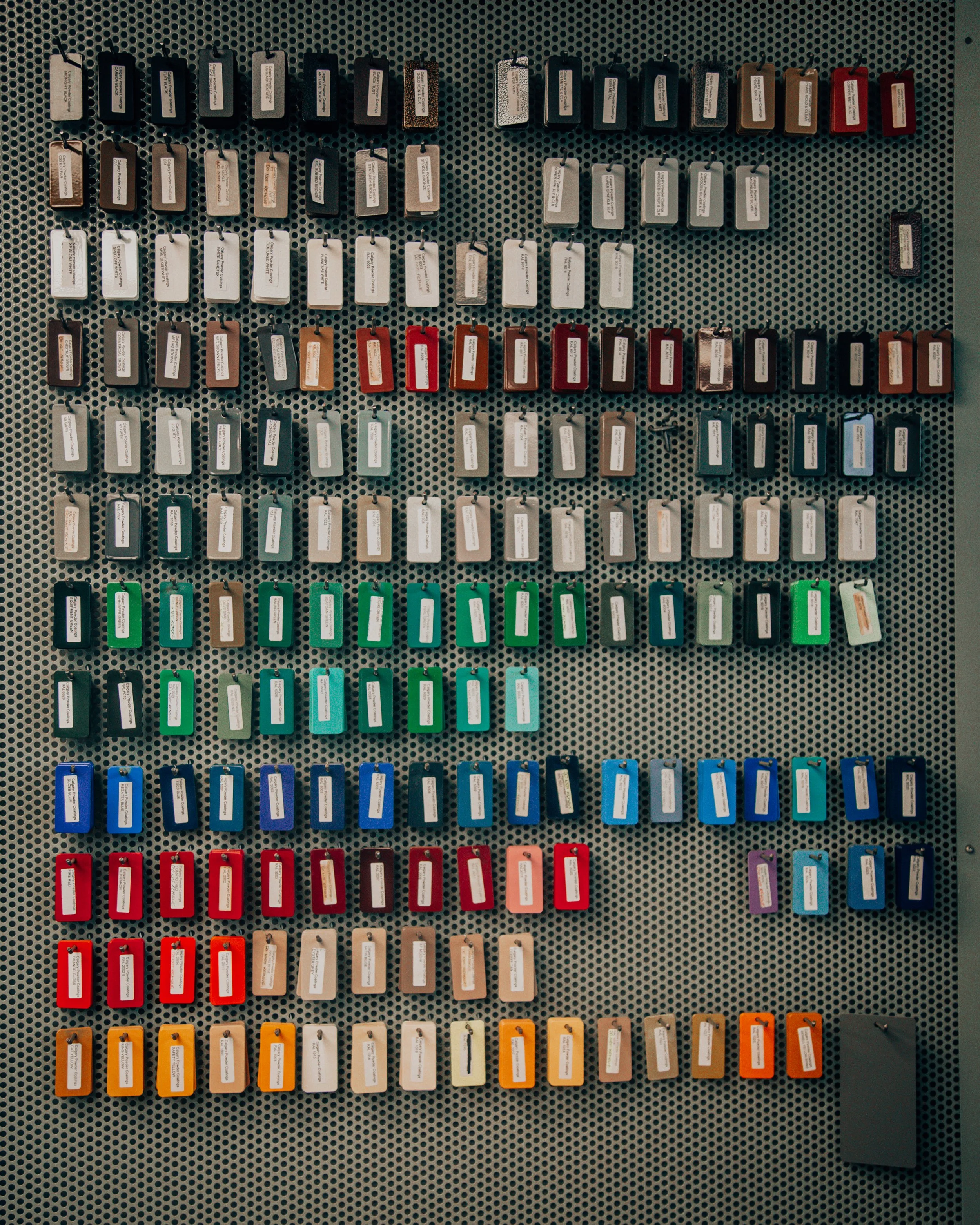 A display of keychains in various colors arranged in rows on a perforated metal surface.